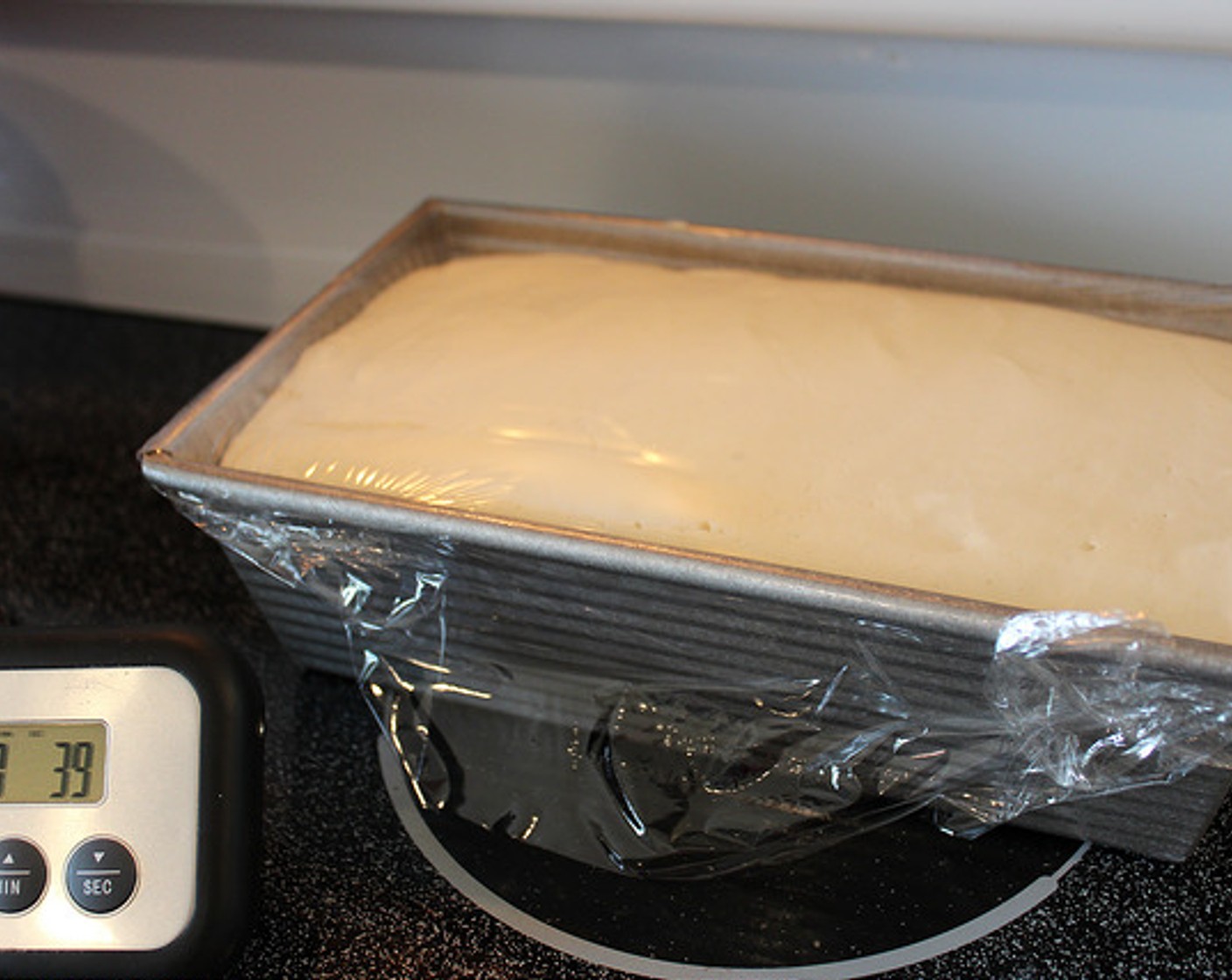 step 11 Using a spatula, scrape the bread mixture into your prepared loaf pan and cover with plastic wrap. Set pan on top of your warm stove to proof while the oven is preheating.