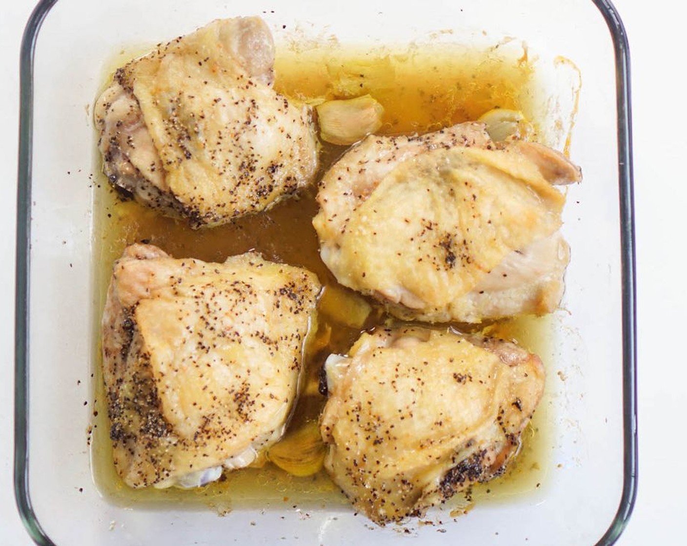 step 2 Wash and dry the Bone-in, Skin-on Chicken Thighs (4). Rub with Olive Oil (3 Tbsp) and sprinkle with Salt (to taste) and Ground Black Pepper (to taste). Place in roasting pan with Garlic (3 cloves) and bake 30 minutes.