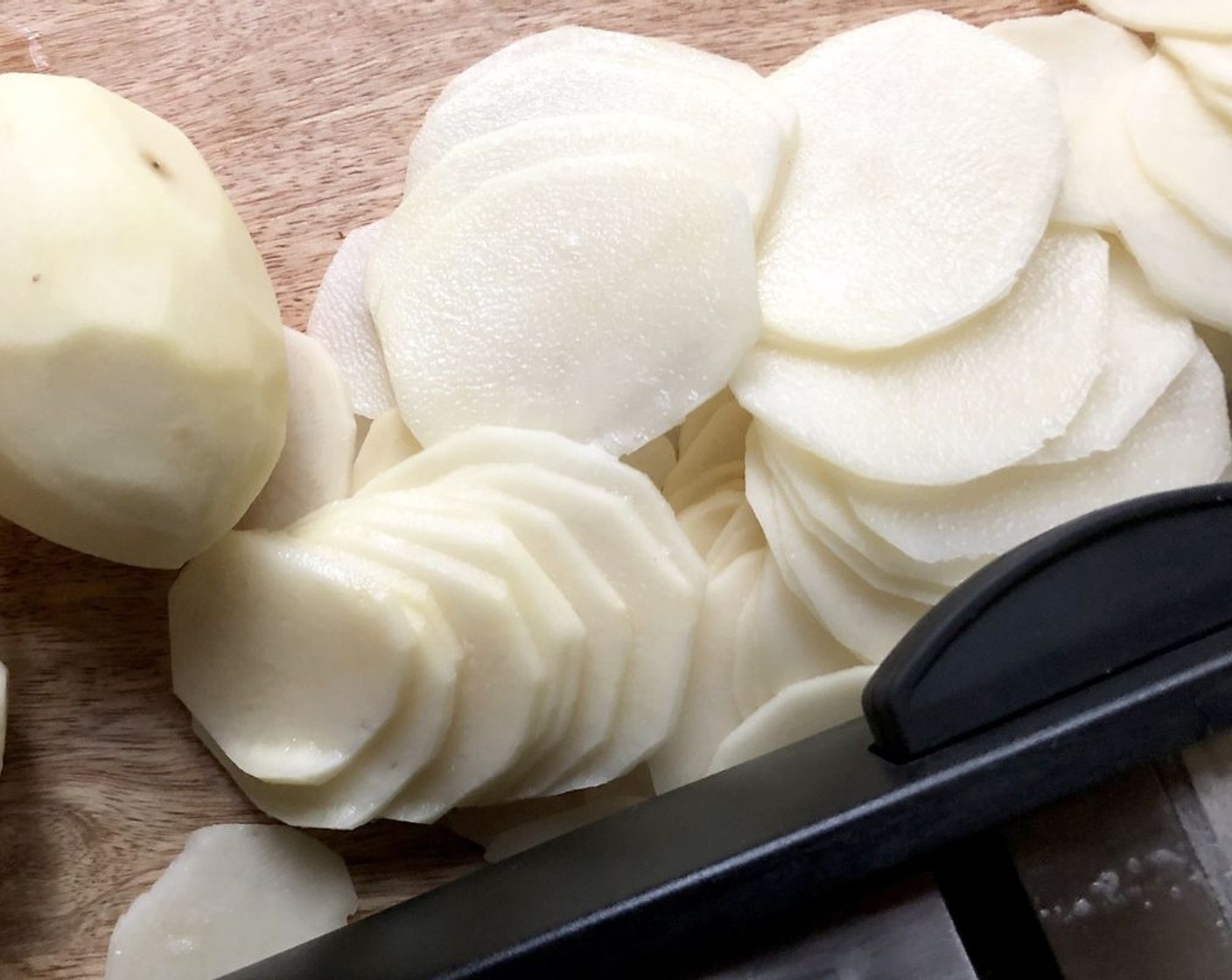 step 5 Using a knife or mandolin, cut the Russet Potatoes (3) into slices ⅛-inch (3 mm) thick.