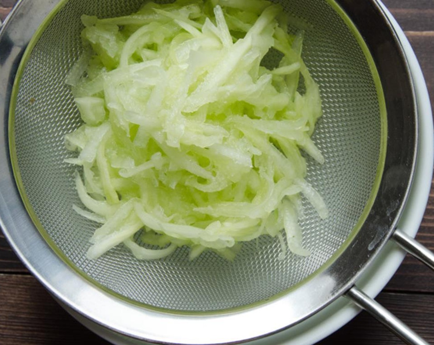 step 12 For the Tzatziki, mince the Garlic (1 clove) and zest the Lemon (1). Peel the Cucumber (1/2) and grate it. Place the cucumber in a sieve over a bowl. Add a pinch of salt to the cucumber and let the water drain out of it for 5 minutes.
