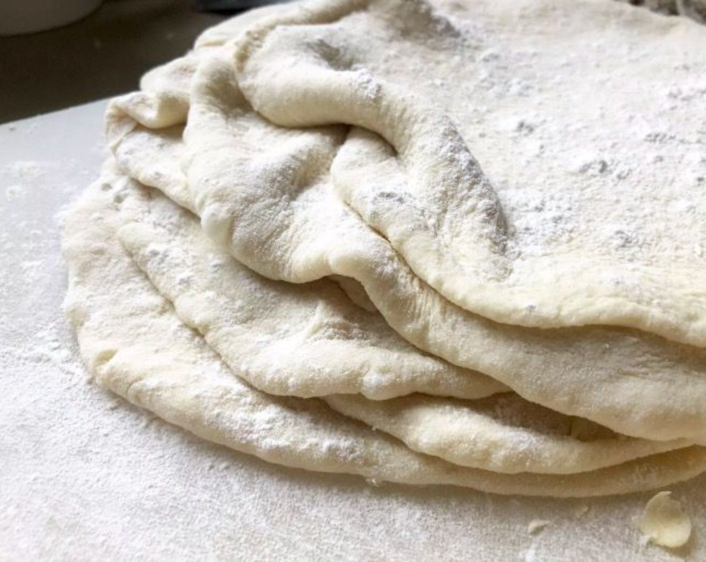 step 7 When ready to cook, divide the dough into 8 equal balls. On a lightly floured surface, roll each one into a large oval about 8 inches in length and about 1/4-inch thick. As you form the ovals and stack them in a pile, be sure to sprinkle them with flour to prevent sticking.