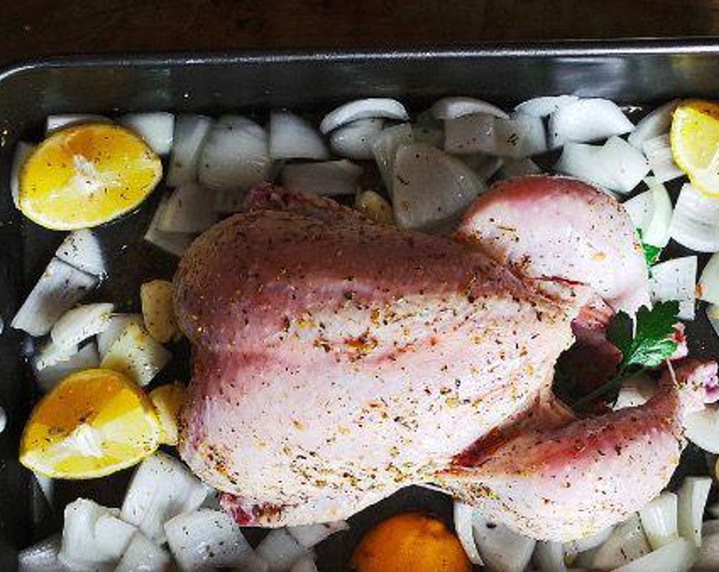 step 4 Arrange the Onion (1) in a large roasting pan. Crush the remaining Garlic (5 cloves) and add to the onions. Add the chicken over top, breast side up. Drizzle with Olive Oil over both the vegetables and chicken, rubbing to coat the entire chicken.