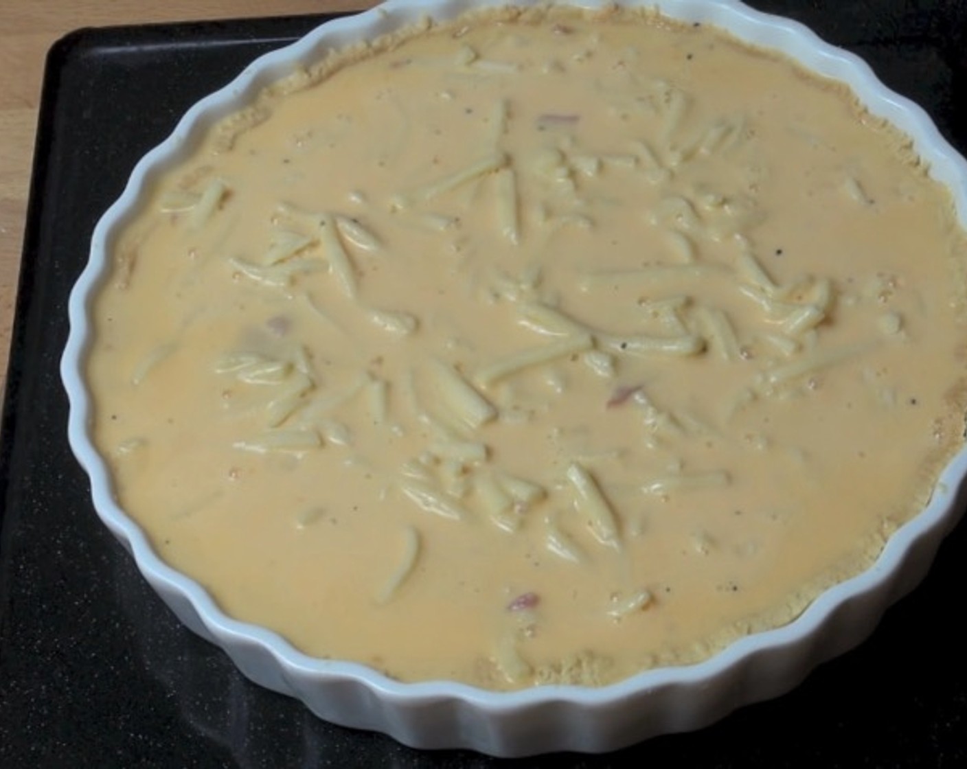 step 9 Spoon the bacon and onion mixture into the pastry base. Sprinkle Cheddar Cheese (1 cup) on top. Pour the egg and cream mixture over the quiche.