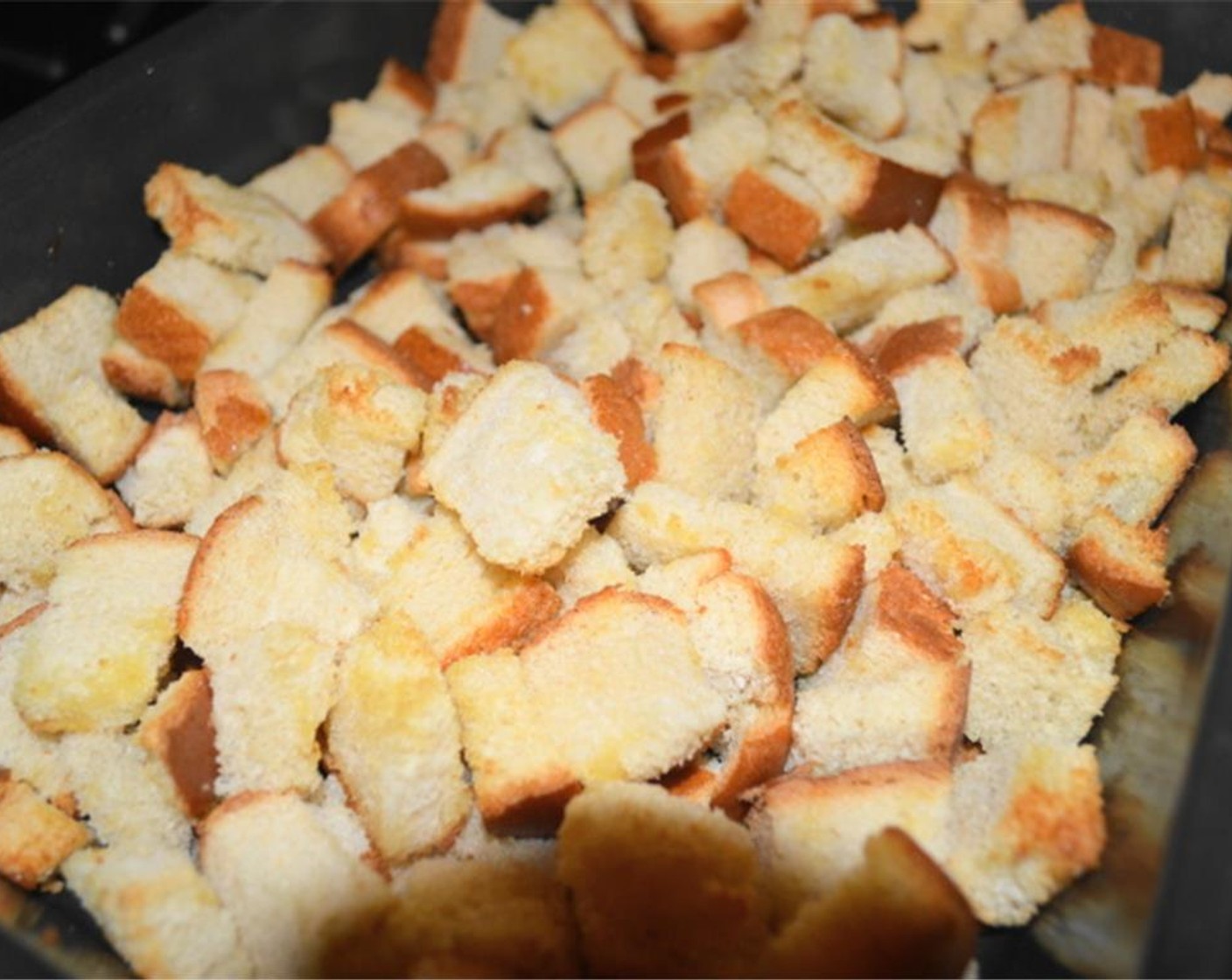 step 2 Get the cubes of White Bread (12 slices) into the pan and toss the cubes with the Extra-Virgin Olive Oil (3 Tbsp). Put the baking pan in the oven to crisp up for about 10 minutes. When it's done, take the pan out and set it aside.