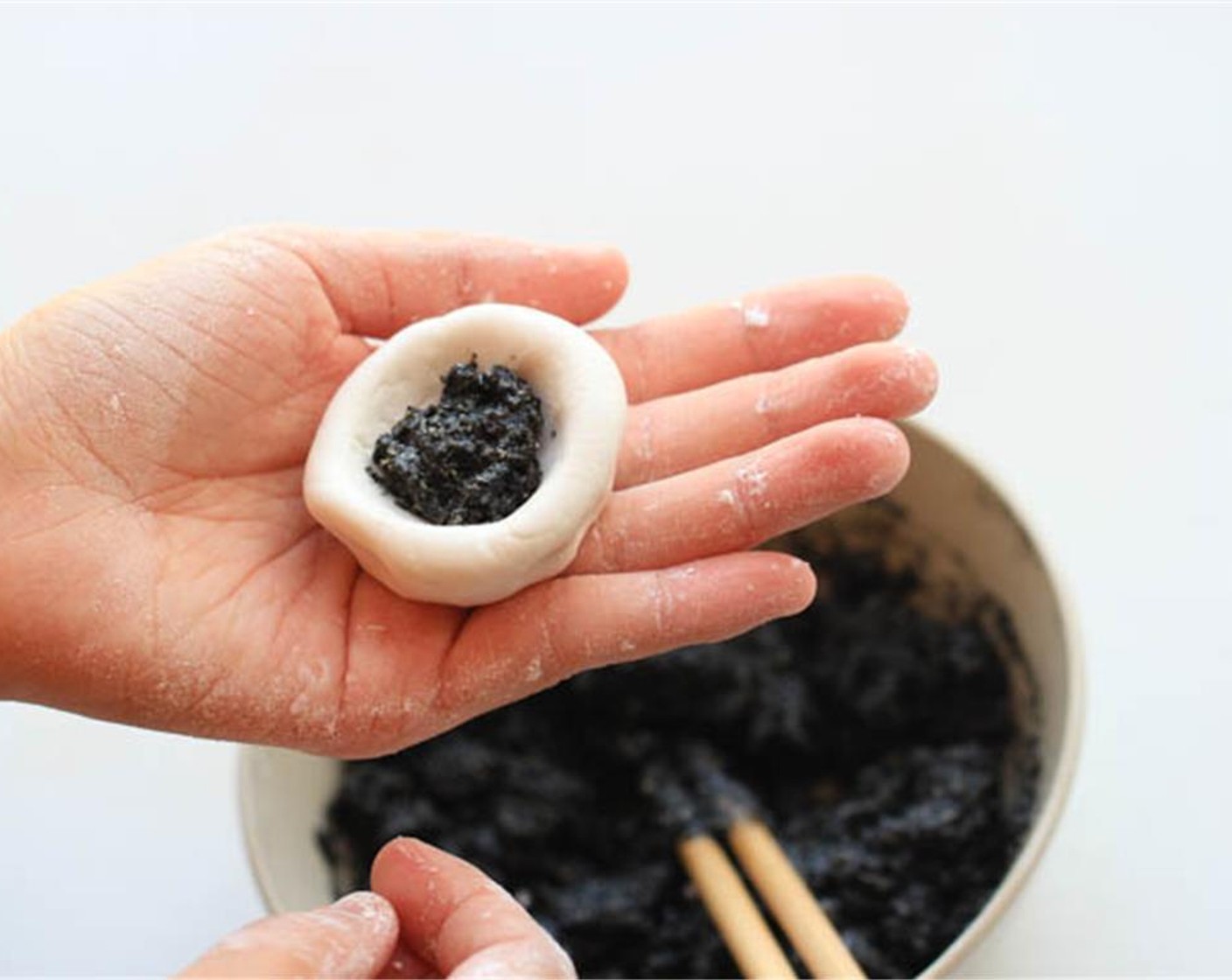 step 6 Take one piece and shape it into a bowl, then scoop around 1/2-1 Tbsp of toasted black sesame filling into the center. Seal the rice dumpling completely and make it as round as possible.