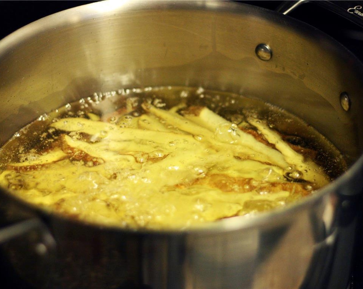 step 6 Place the pot over medium heat. Once the oil begins to bubble, continue to cook, uncovered, for 10-15 minutes. Use a heat-safe spatula to occasionally loosen the strips and turn them, taking care not to splash hot oil on yourself.