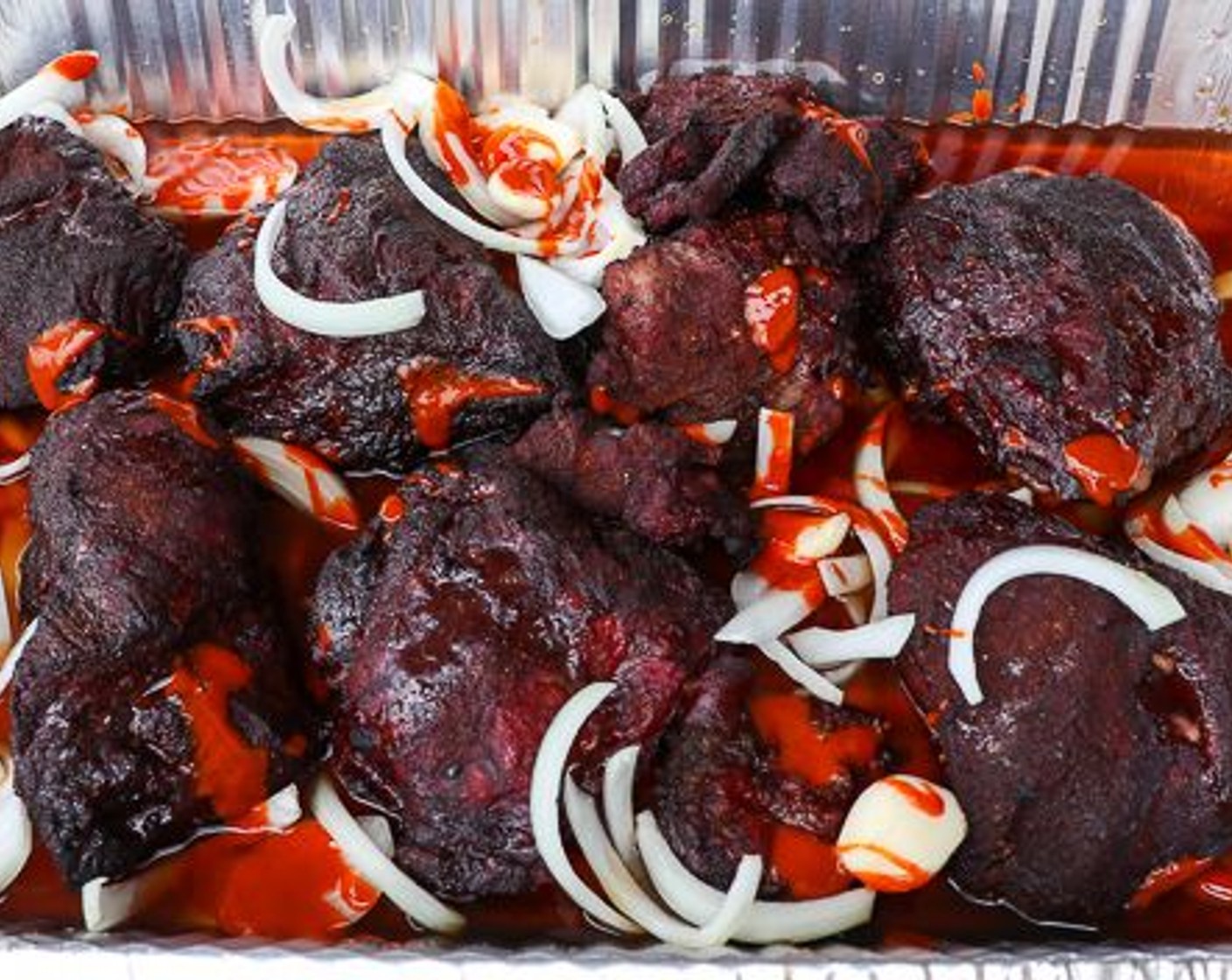 step 4 Remove beef cheeks from out and place in aluminum pan. Add Onion (1), Garlic (10 cloves), Beef Stock (3 cups) and Mexican Style Hot Sauce (1/4 cup).