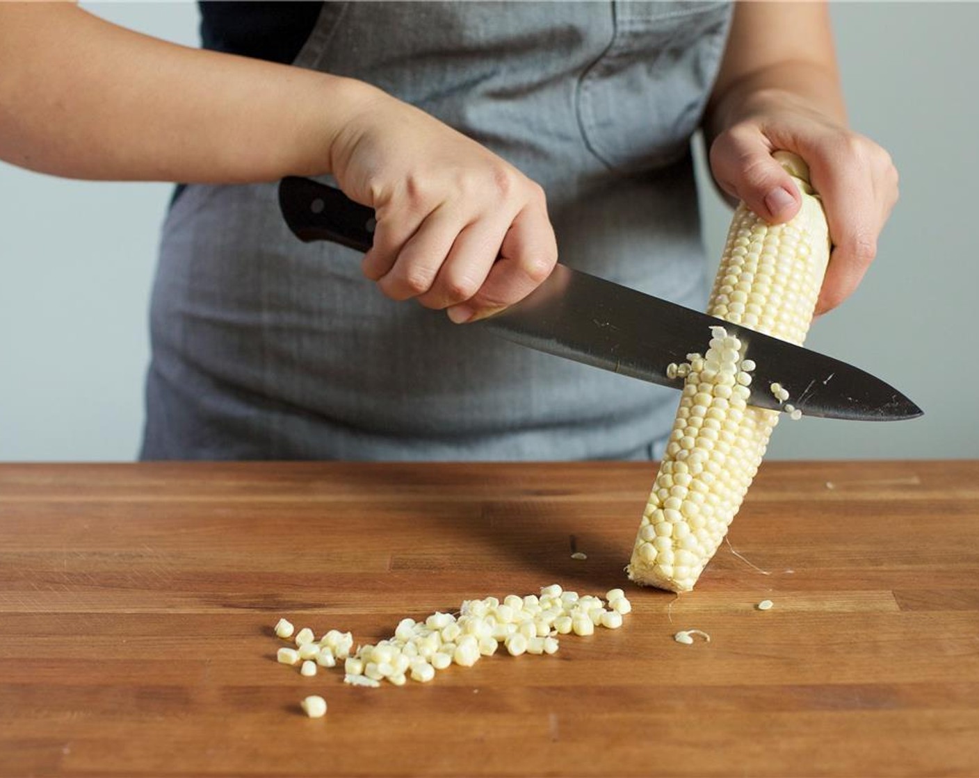 step 2 Meanwhile, place the Corn (1 ear), cut side down, on the cutting board, holding it near the top of the ear. Continue cutting until all of the corn is removed.