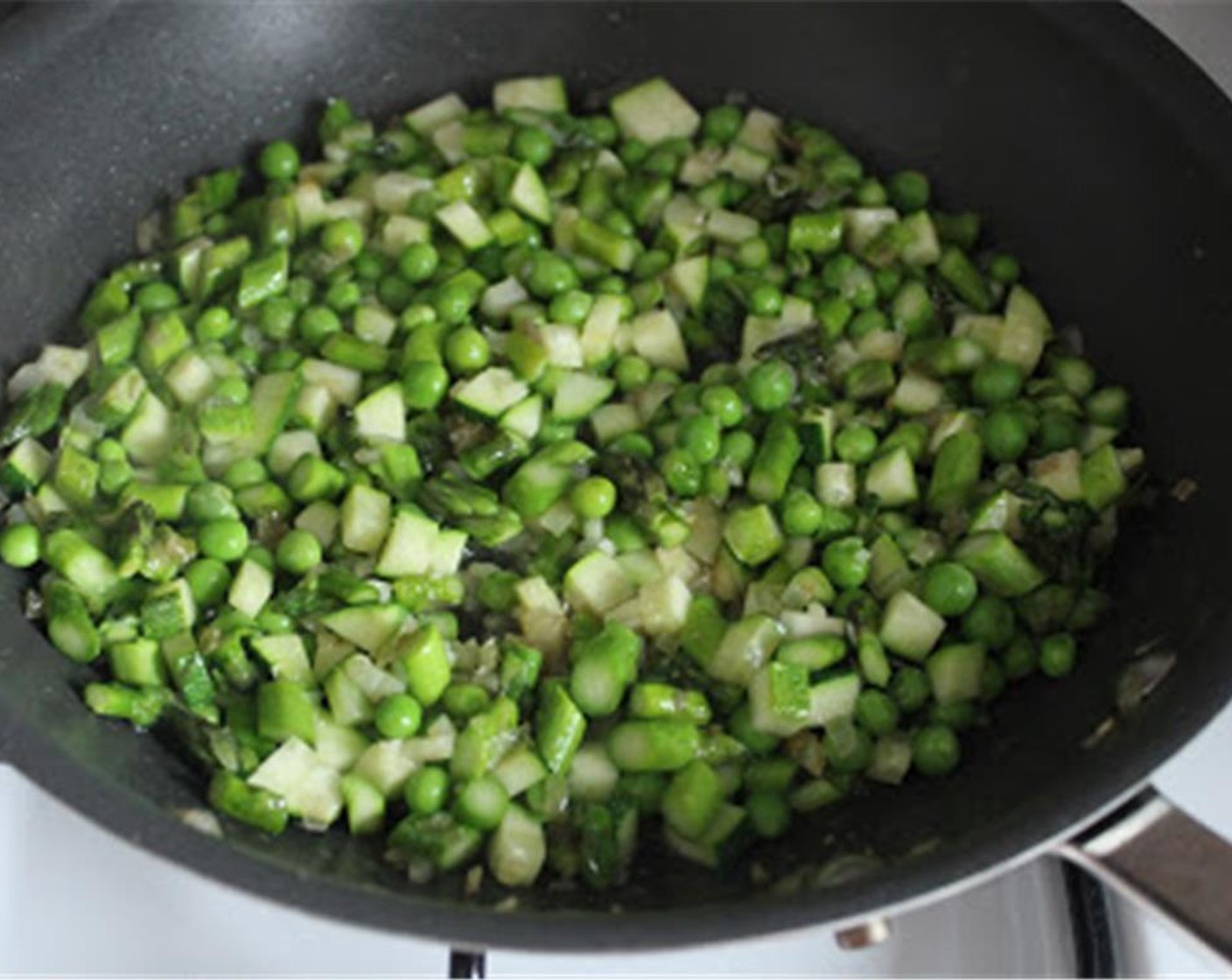 step 5 Add the shelled fresh peas, asparagus, and zucchini to the pan. Cover and cook for 3 minutes over medium heat until just tender.