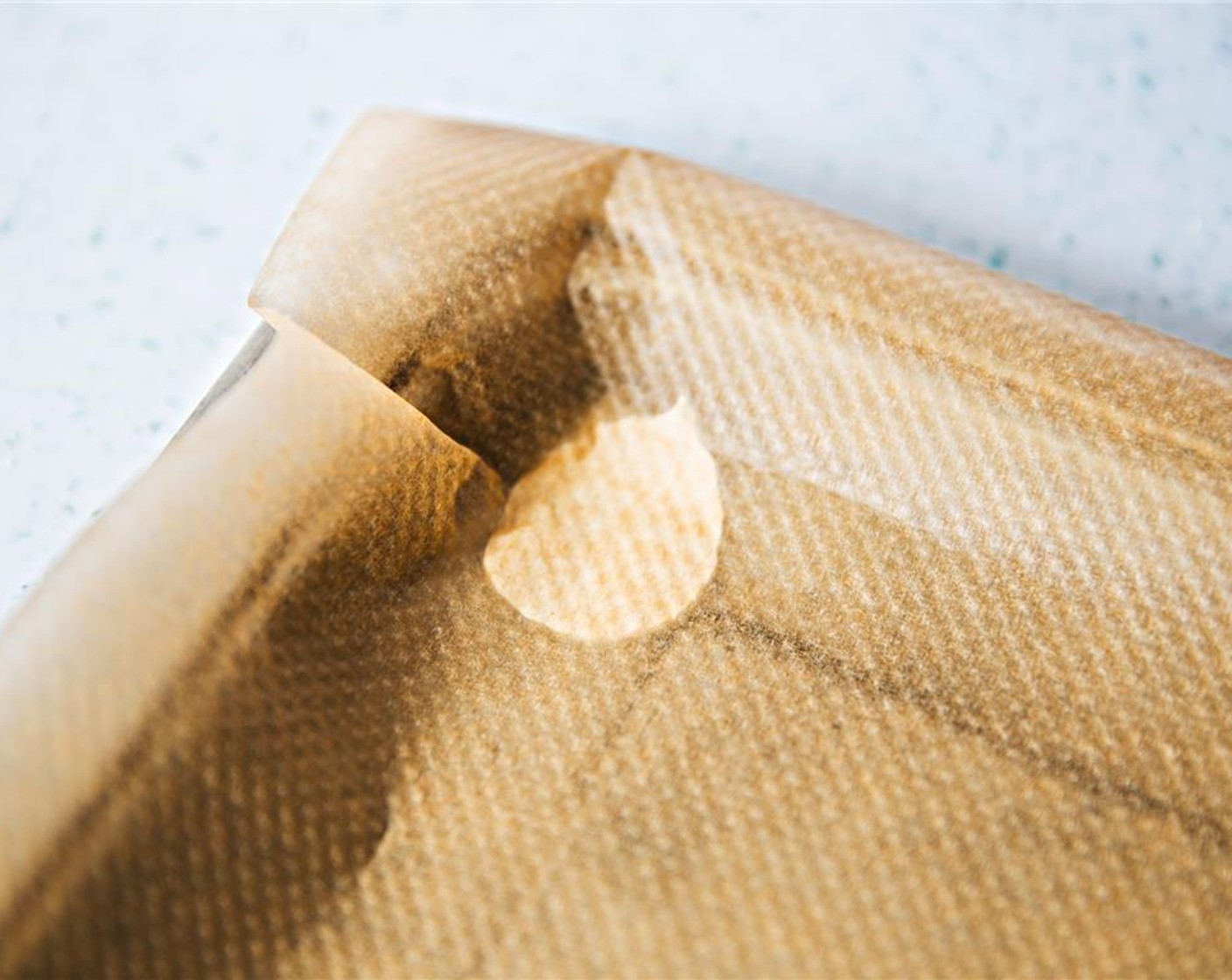 step 7 Prepare baking tray by putting small dabs of the mixture into the four corners, and overlay parchment. Secure by pressing down on each corner.