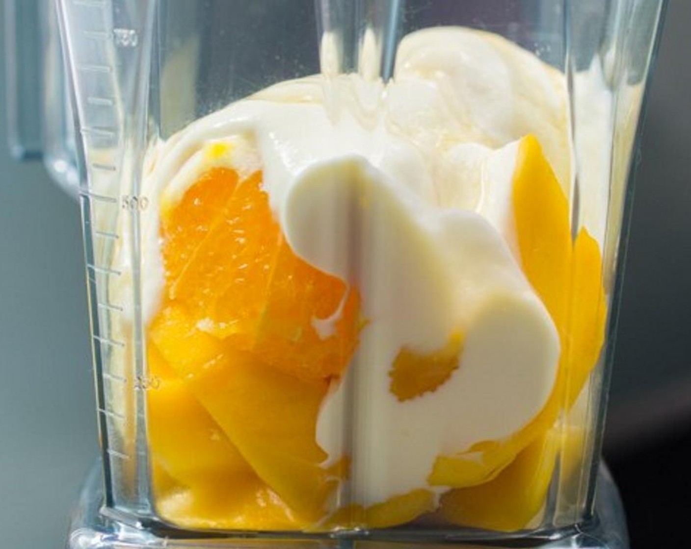 step 3 Put the cut mango and orange halves into a blender. Add plain Plain Greek Yogurt (1/2 cup), Milk (1/2 cup), Honey (1 Tbsp) and Ice (1 cup).