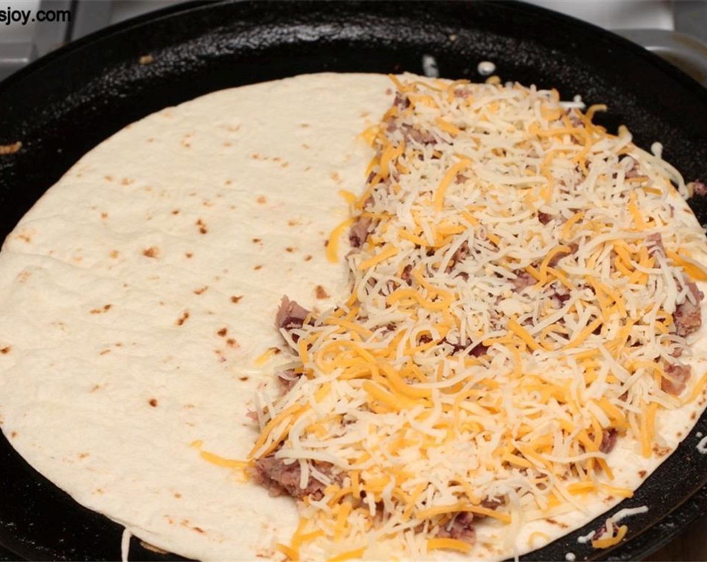 step 5 Heat a griddle and place a Tortillas (4) on it. Spread the bean mixture on one half of it and sprinkle with Cheese (1 cup).