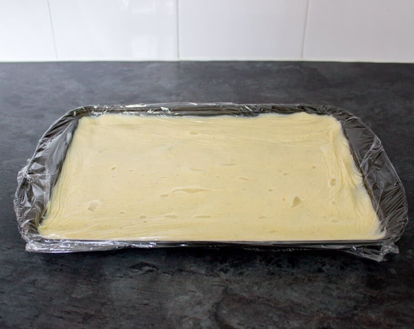 step 20 Spread it over a baking sheet and cover with cling film, making sure the film actually touches the surface of the creme patissiere. This will stop a skin from forming. Place in the fridge until needed.