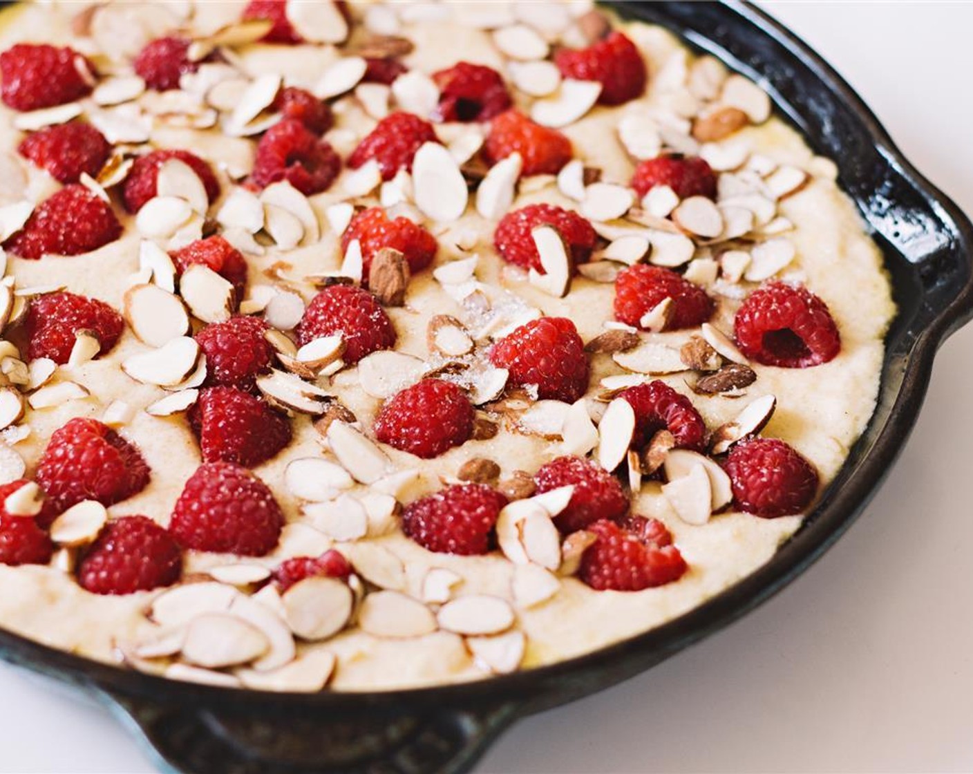 step 9 Pour the batter into the buttered skillet and arrange the remaining fruit atop the cake. Scatter on the Sliced Raw Almonds (4 Tbsp) and Granulated Sugar (2 Tbsp).
