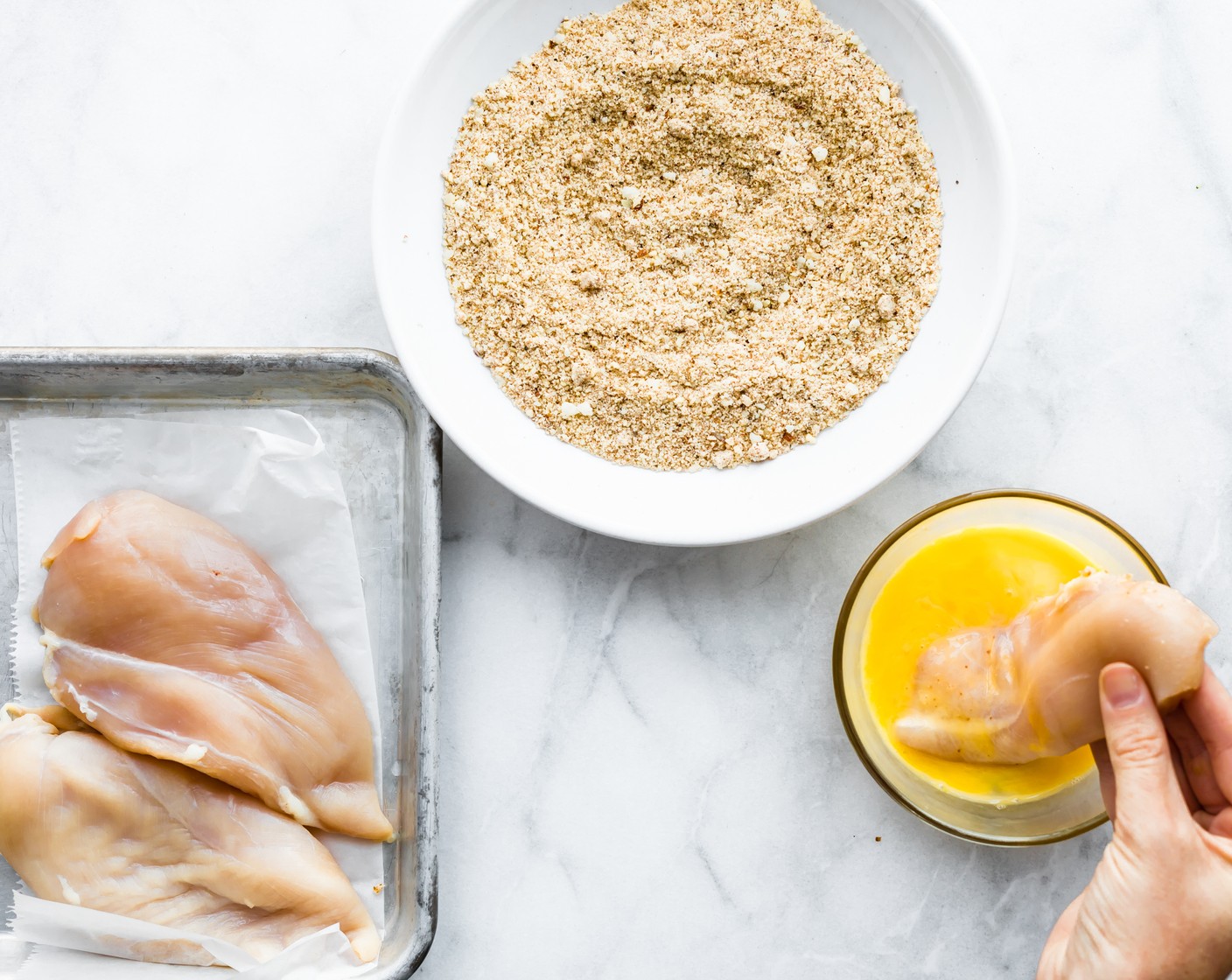 step 5 Dredge chicken in beaten eggs and then into the almond mixture. Place on a baking sheet, leaving room for veggies on one side of the pan.