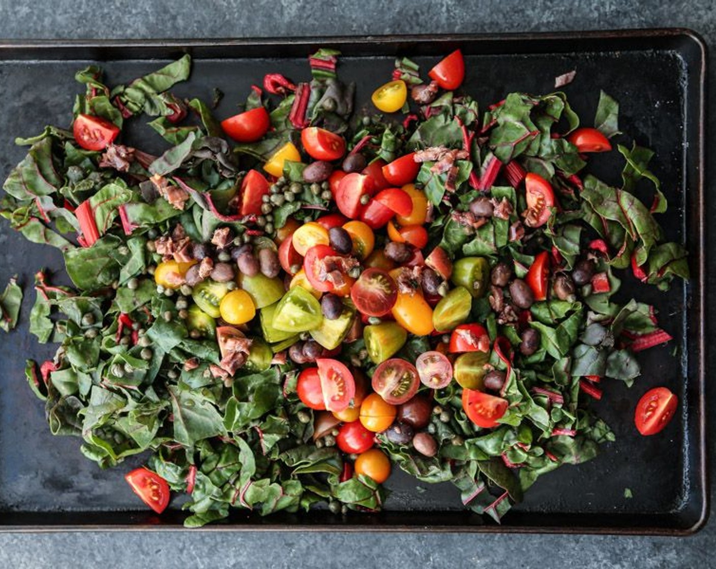 step 2 On a large rimmed baking sheet, toss the Red Chard (1 bunch), Cherry Tomatoes (4 cups), Shallot (1), Garlic (2 cloves), Kalamata Olives (1/4 cup), Anchovy Fillets (2), Capers (1 Tbsp), Olive Oil (1/4 cup), and Sea Salt (1/2 tsp) until combined.