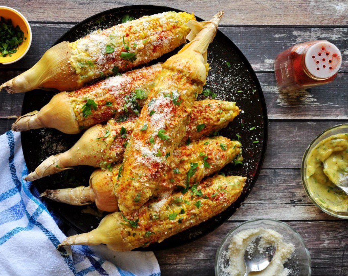 step 9 Coat 2 tablespoons aioli on each corn. Make sure that all sides are covered. Sprinkle with Paprika (to taste) and Parmesan Cheese (to taste). To finish off, top with the remaining Fresh Parsley (1 Tbsp).