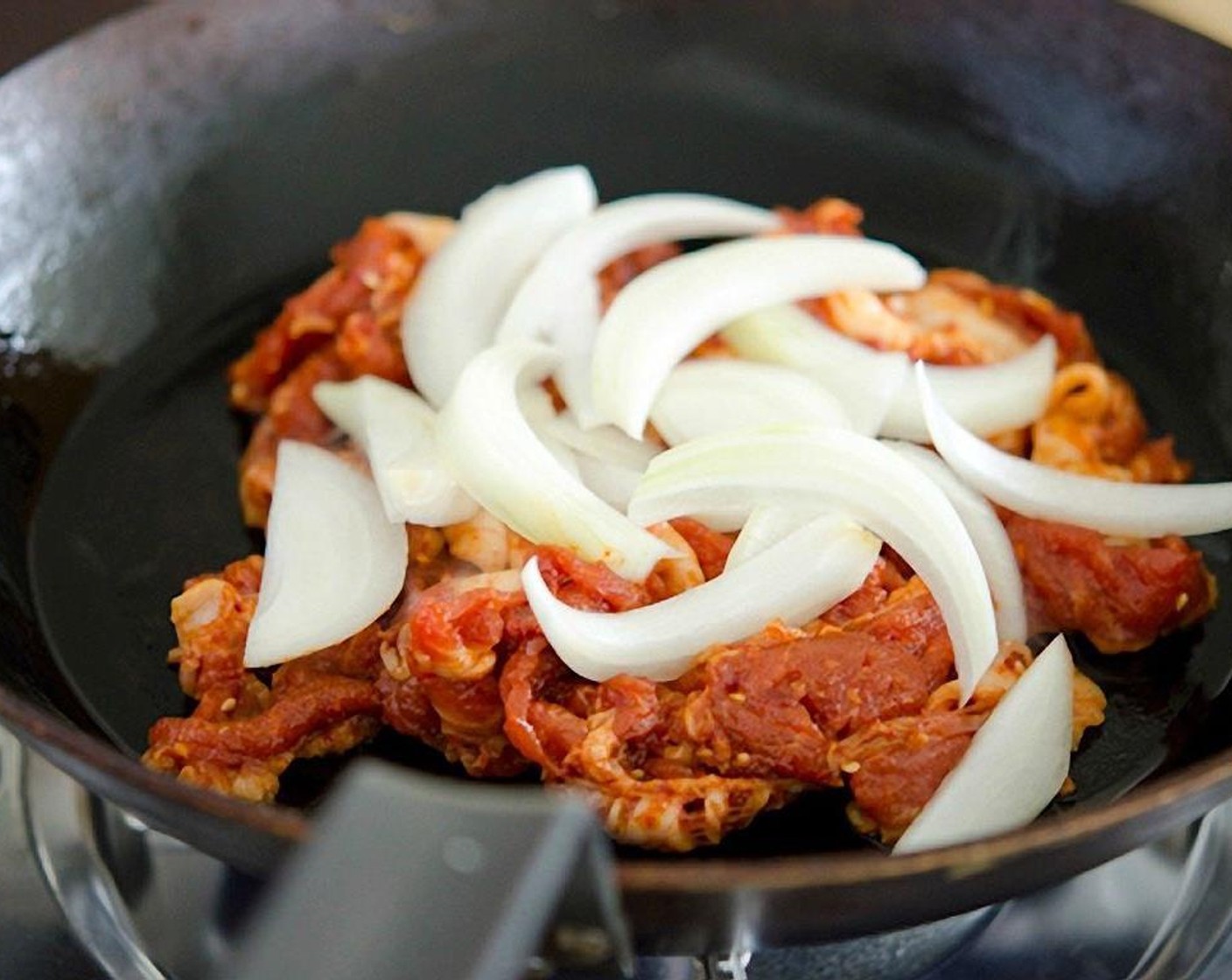 step 8 Drizzle Canola Oil (1 Tbsp) into the skillet and place it over medium-high heat. Place pork over the skillet and add the sliced onion on top.