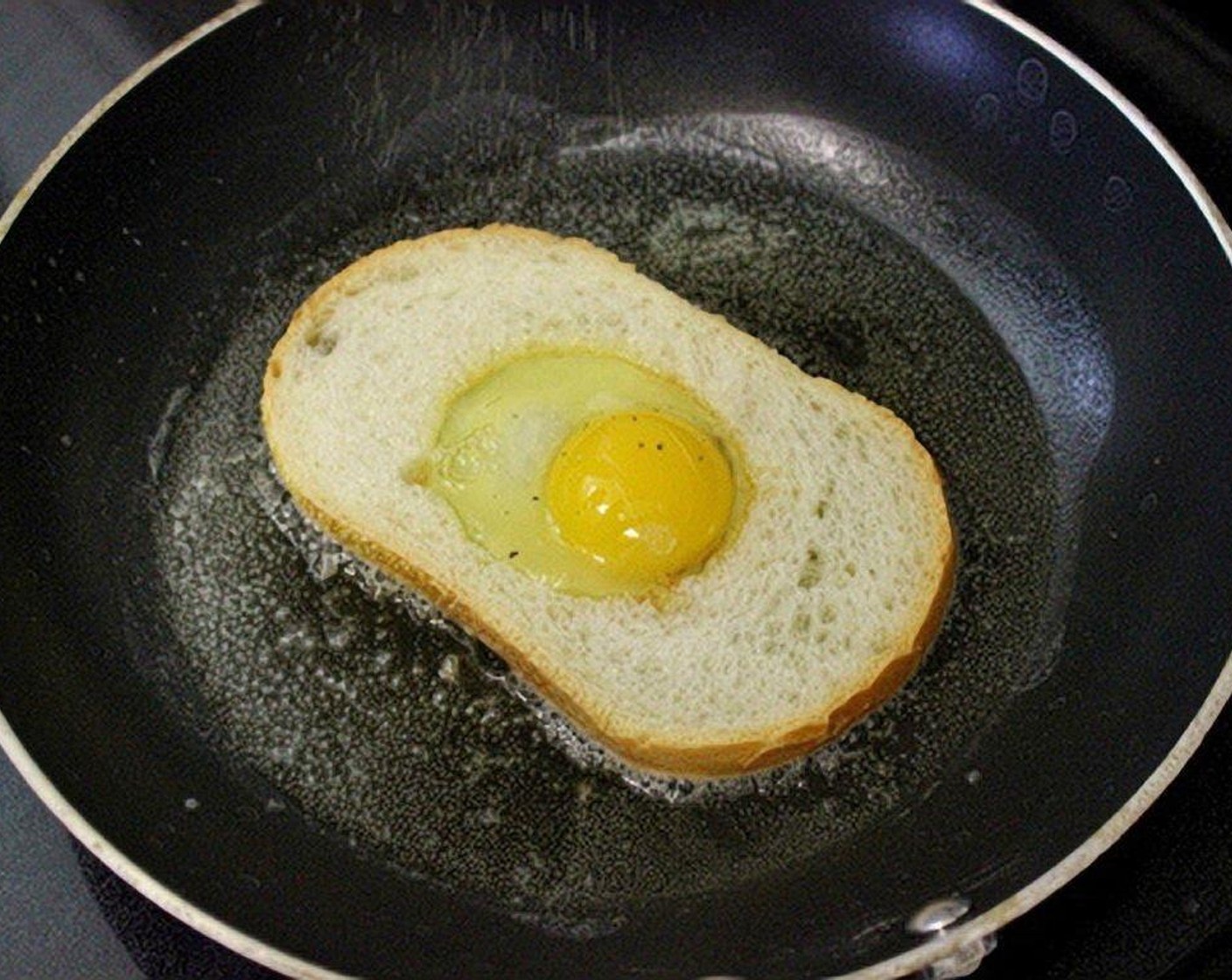 step 4 Crack one Eggs (4) into the center of each slice of bread. Season with Salt (to taste) and Ground Black Pepper (to taste).