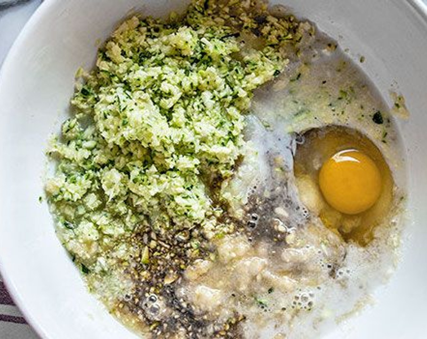 step 3 In a medium bowl, add Zucchini (1 cup), Banana (1), Raw Honey (1/3 cup), Unsweetened Apple Sauce (1/3 cup), Unsweetened Vanilla Almond Milk (4 Tbsp), Eggland's Best Classic Egg (1), and Vanilla Extract (1 tsp). Whisk to combine, slowly stir in the Coconut Oil (2 Tbsp), and continue to stir until combined.