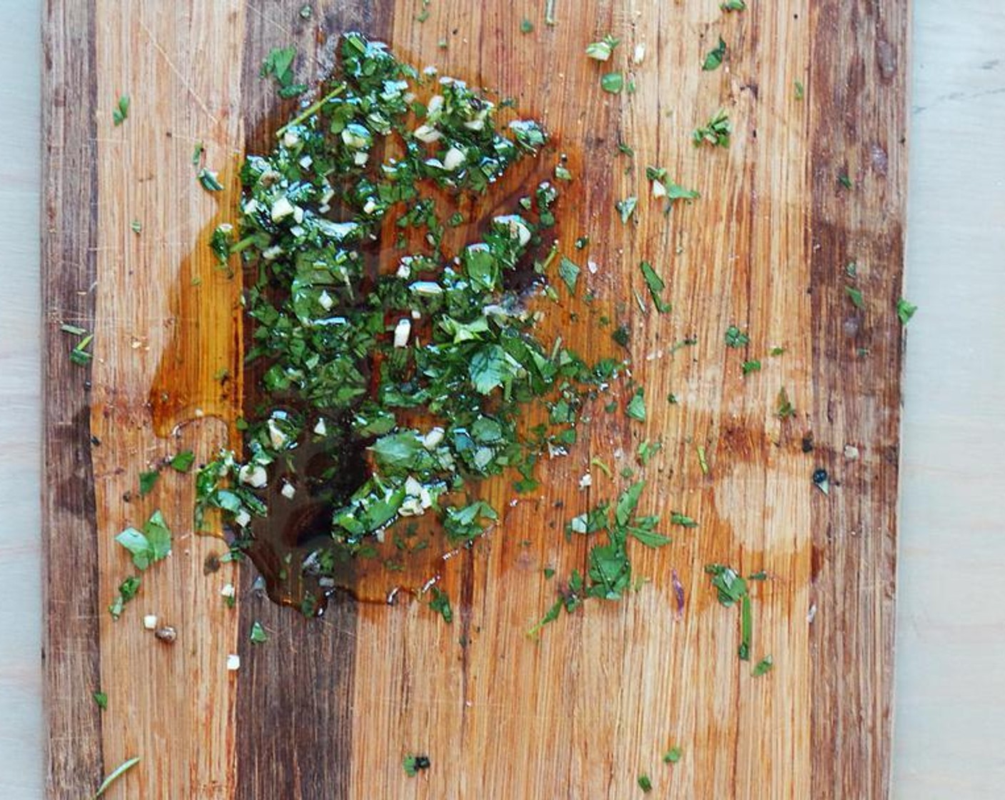 step 5 While this is cooking, whip up the board sauce. On a cutting board, prepare the Fresh Herbs (2 Tbsp) and drizzle over the Olive Oil (1/3 cup) and a splash of the Balsamic Vinegar (to taste).