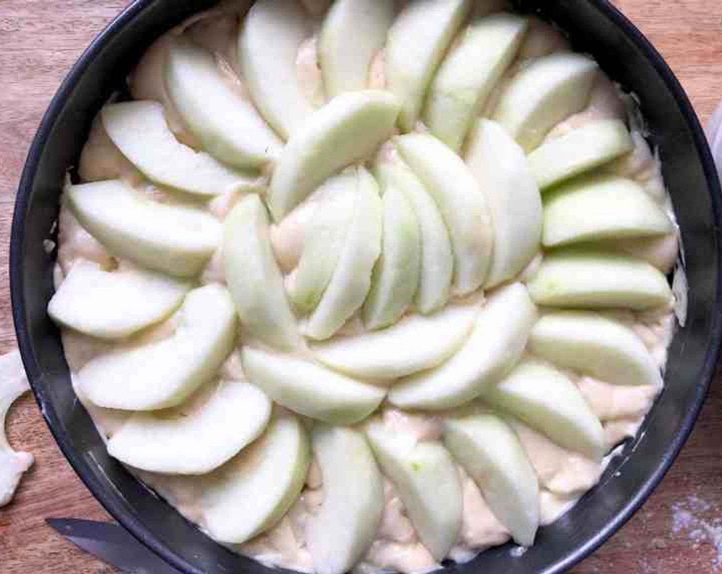 step 8 Scrape the batter into the prepared pan and smooth the top. Distribute the sliced apples decoratively in concentric rings on the top of the cake.