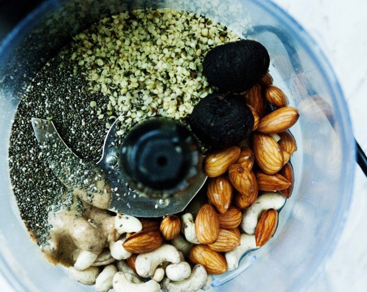 step 2 Place almonds, cashew nuts, Almond Butter (1/2 cup), Chia Seeds (2 Tbsp), Hemp Hearts (2 Tbsp), Coconut Oil (1 Tbsp), Himalayan Rock Salt (1/4 tsp), Hemp Protein Powder (1 scoop), Coconut Syrup (1 Tbsp) and Black Garlic (2 heads) into a food processor.