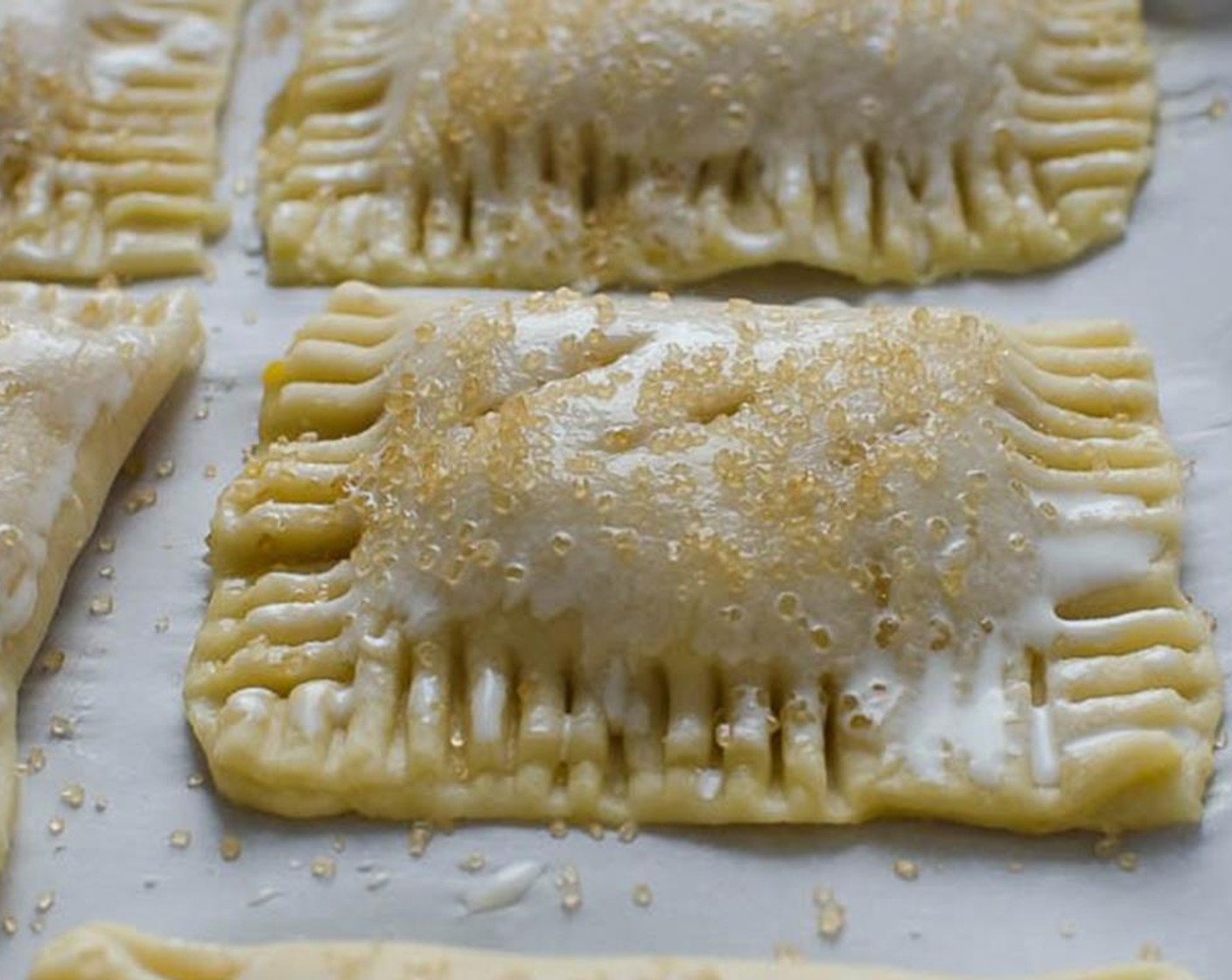 step 9 Using a pastry brush, brush Egg (1) along the edges of the pastry. Fold the dough over and press a fork along the sides. Transfer the pie to the baking sheet. Cut a few vents about 1/2" long. Brush the pies with Cream (1/4 cup) and sprinkle with Demerara Sugar (1/4 cup)