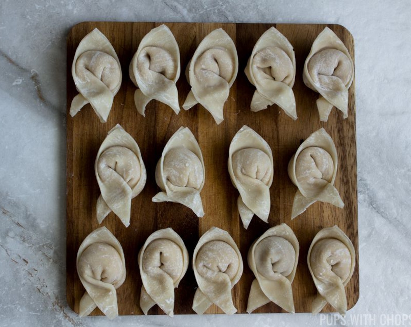 step 12 While holding the ‘wings’ of the dumplings with your finger and thumb, press your fingers towards each other until the ‘wings’ overlap and then press down where you dabbed the water to hold it in place.