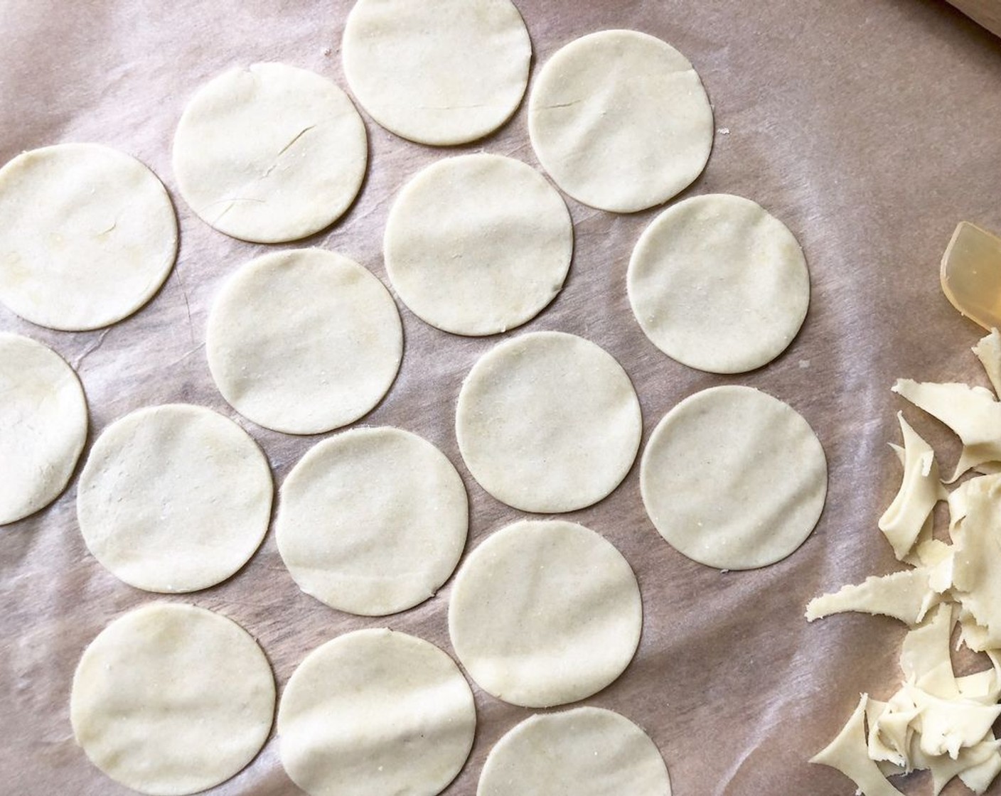 step 7 Cut out the crackers with a 2-inch round cookie cutter as closely as possible. Pull up the outline of the dough, leaving the round cutouts on the paper. Slide the paper onto the preheated baking sheet.