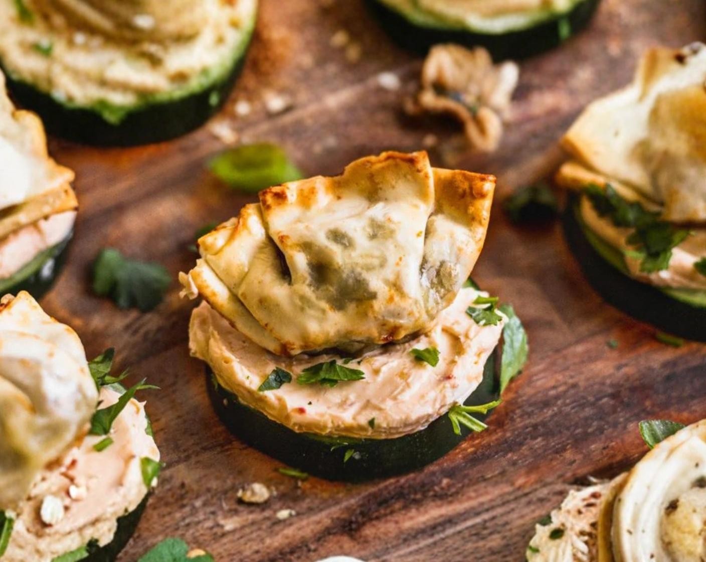 step 3 Prepare the bites by spreading approximately ½ to 1 tbsp of the cream cheese mixture on each Cucumbers (16 slices) round, sprinkle with Fresh Cilantro (4 Tbsp) and top with a wonton. Serve immediately.