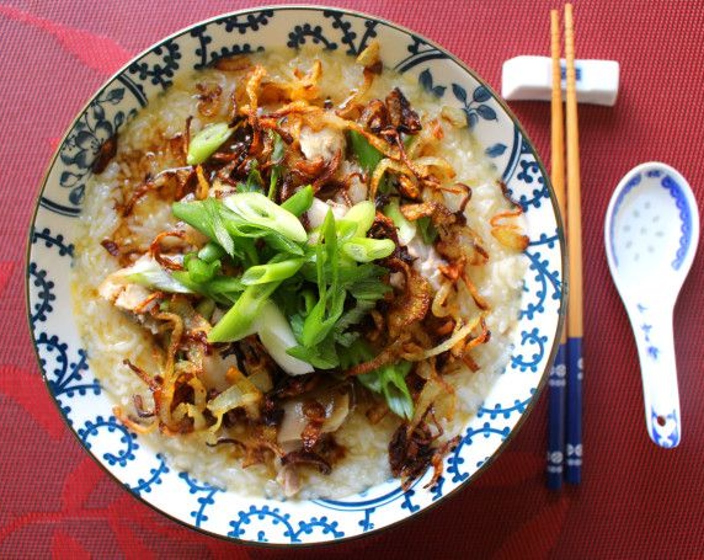 step 5 Ladle the porridge into 4 deep bowls, top with the diced pork, drizzle with Sesame Oil (to taste), Chili Oil (to taste), and Soy Sauce (to taste), sprinkle with Scallions (to taste) and the fried onion.