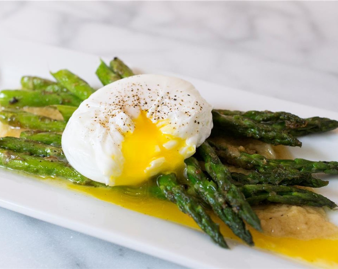 step 12 Divide the warmed roasted garlic miso butter between two plates. Add the asparagus and top each with an egg. Season with freshly ground black pepper, and serve immediately.