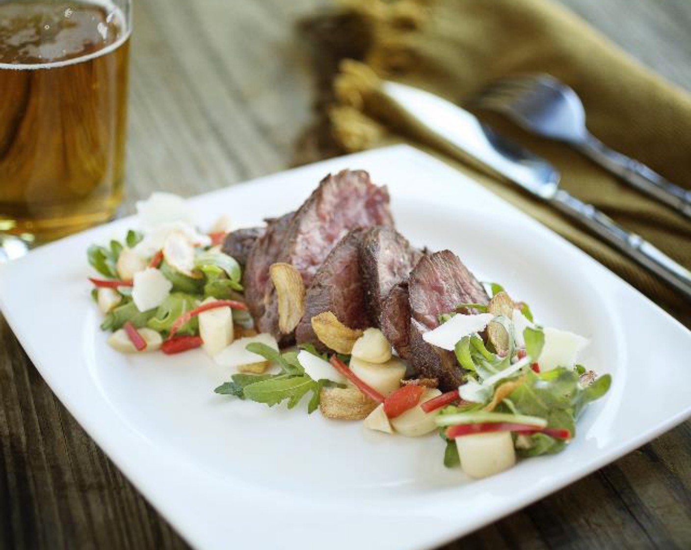 step 15 Arrange the steak slices on top of the salad. Garnish with chopped almonds, the garlic chips and Shaved Parmesan Cheese (1/4 cup). Drizzle the remaining dressing over the salads. Serve and enjoy!