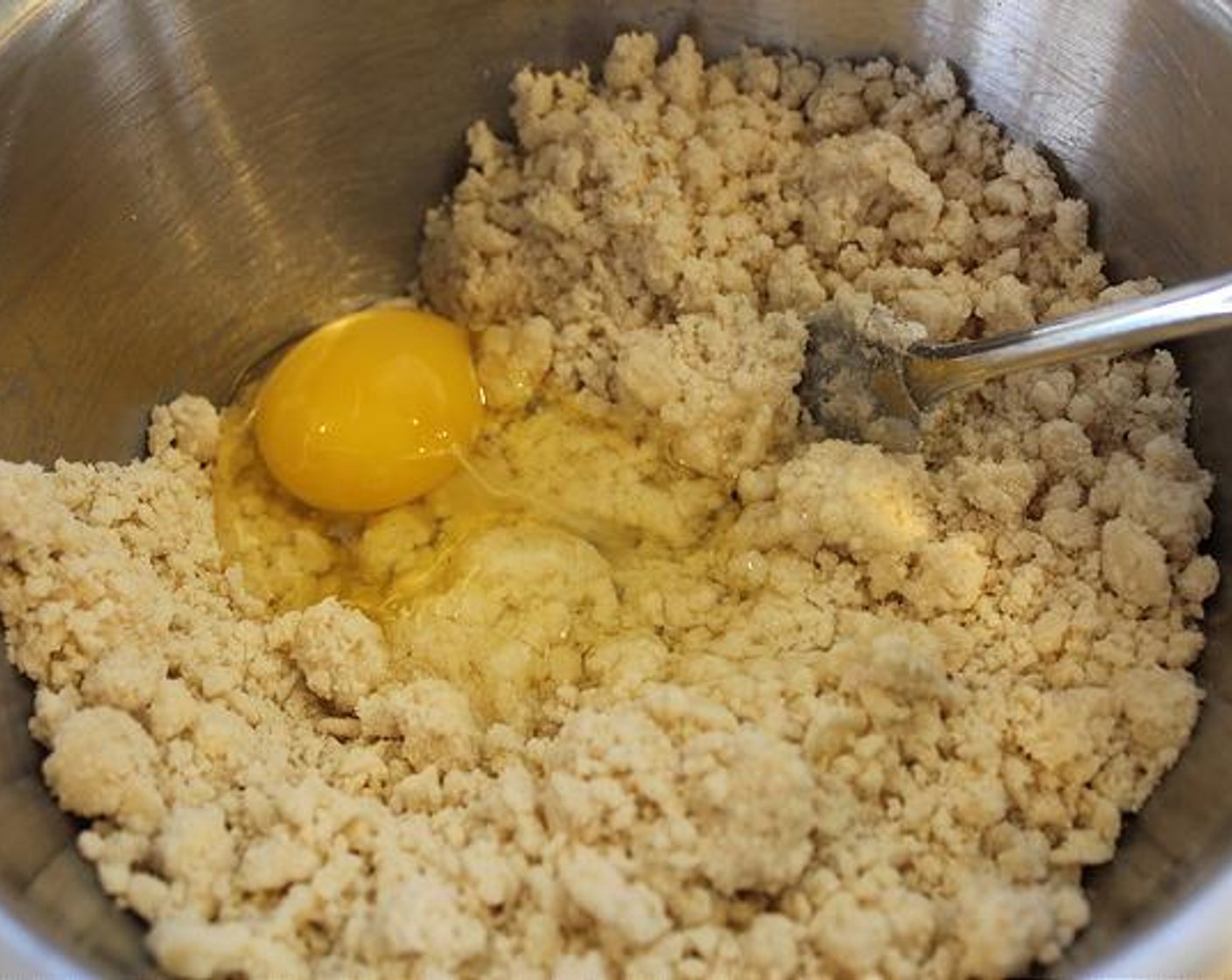 step 2 Add in Egg (1) and mix until well incorporated – mixture will still be crumbly. Add Water (2/3 cup) by stirring in 1 Tablespoon at a time until dough holds together for rolling – better a little moist, then too dry.