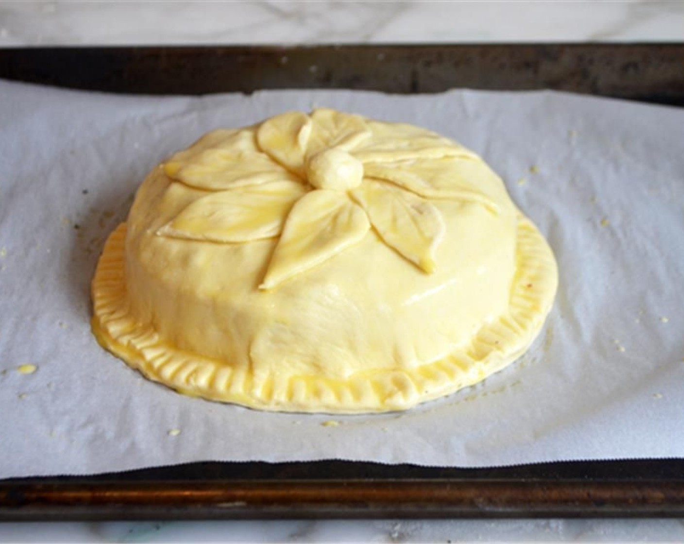 step 9 Decorate the top of the pastry with the leaves, and a berry or two, if you like, then brush the decorations with the egg wash.