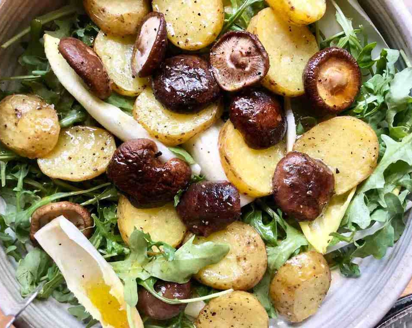 step 11 Just before serving, build the individual salads. Place the potatoes, mushrooms, Baby Arugula (2 cups), and White Belgian Endive (2 heads) in a large bowl and drizzle some vinaigrette over the combo.