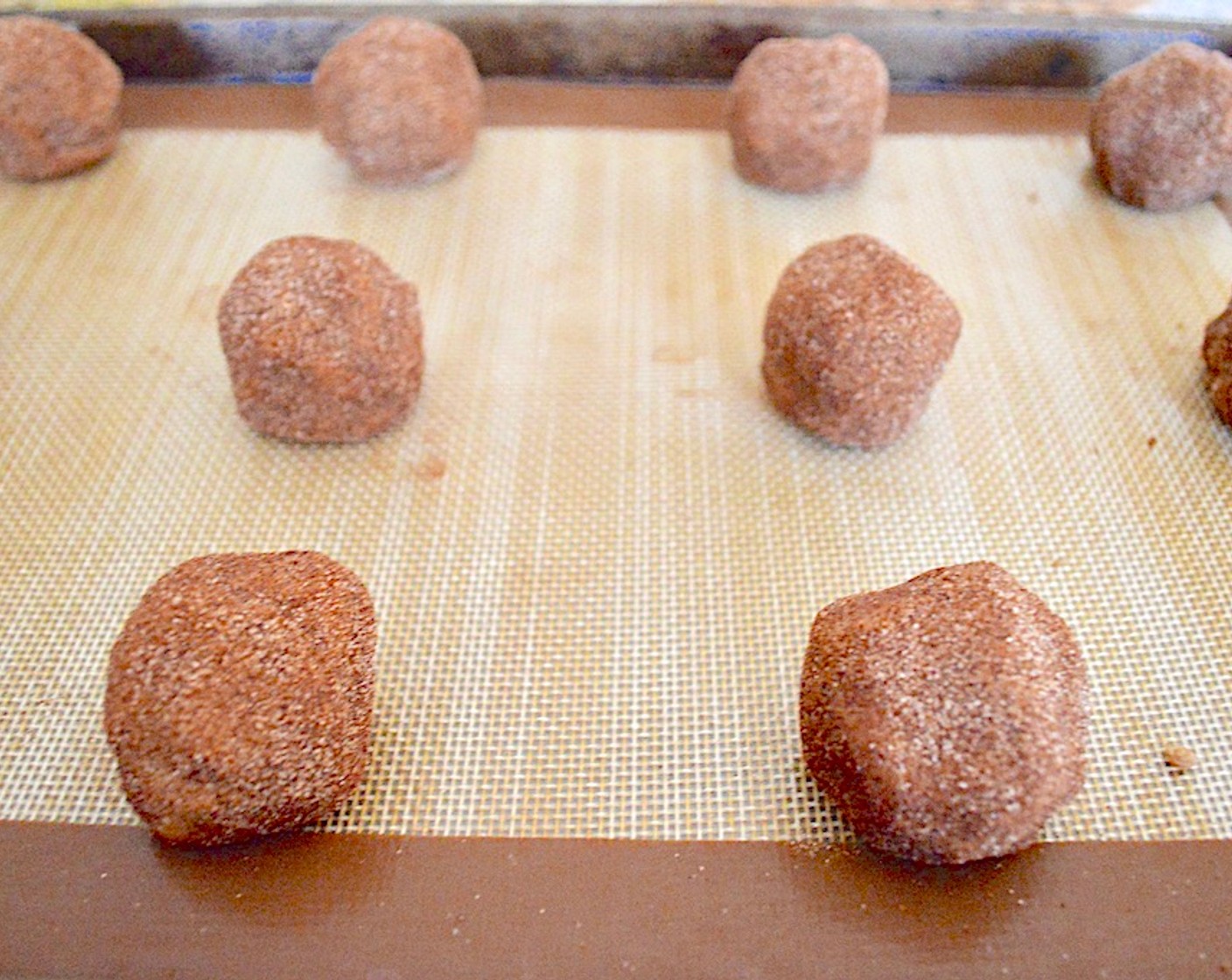 step 9 Bring the sides over to completely enrobe the caramel and roll it slightly to smooth it back into a ball. Roll it through the cinnamon sugar to coat it well and place it on the lined sheet tray. Repeat this process to make a dozen total. Put the tray in the freezer to set everything for 20 minutes.
