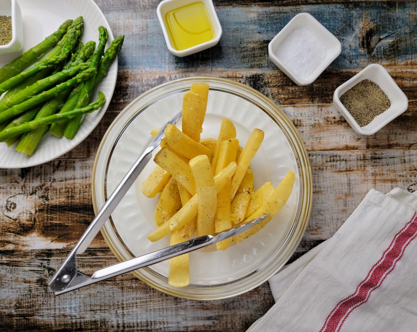 step 4 Line a rimmed sheet pan with parchment paper. Place the Steak Cut French Fries (13 2/3 cups) (about 20 pieces) in a large mixing bowl and toss with Olive Oil (1 Tbsp), Kosher Salt (1 Tbsp), and Ground Black Pepper (1 Tbsp). Lay out the potatoes on one side of the sheet pan. Place the Asparagus (1 2/3 cups) in the same mixing bowl and toss with Olive Oil, Dried Thyme Leaves (1 tsp), Salt, and Pepper. Then place the asparagus spears on the other side of the sheet pan.