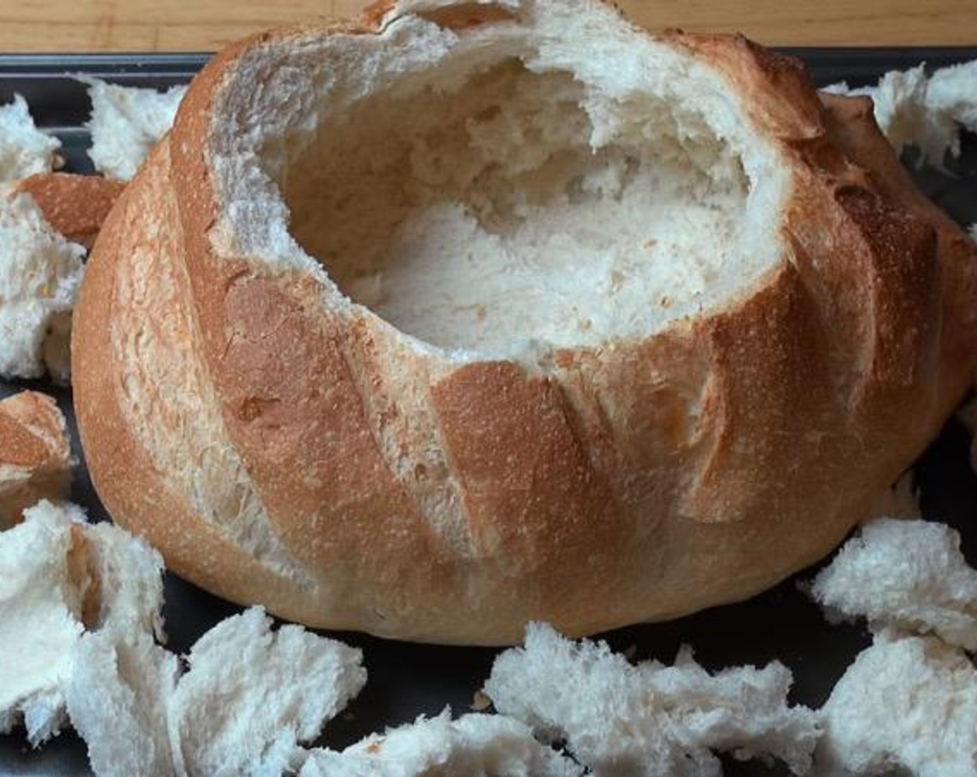 step 1 Cut a lid off the top of the Bread Boule (1). Pull out the bread from the center of the loaf, ending up with an empty bread bowl. On a baking tray, break the lid and inside bread into bite-size pieces and arrange them around the bread bowl.