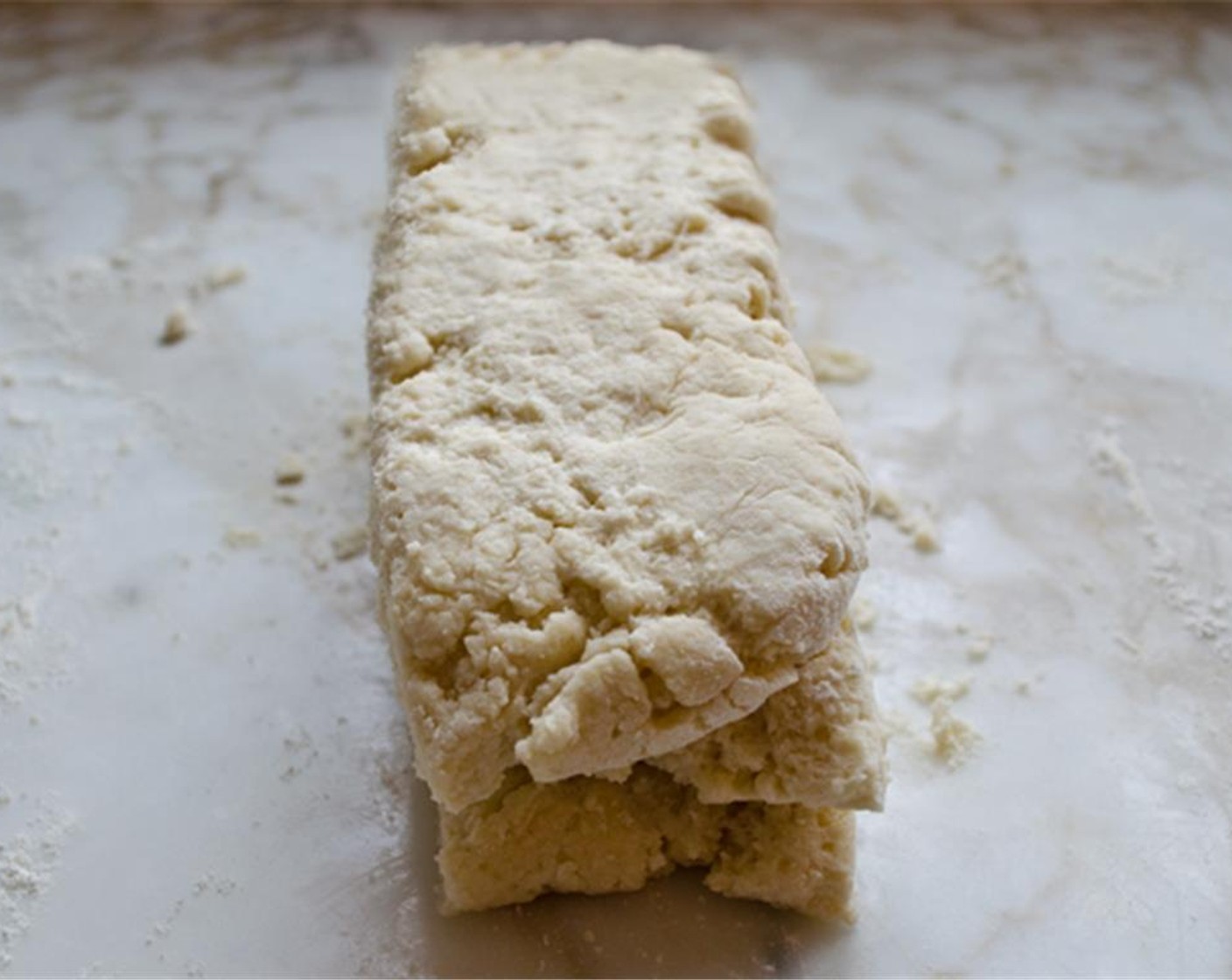 step 6 Using a sharp knife, cut the dough into thirds. Stack the pieces on top of one another and pat out into a 3/4 inch thick rectangle again, flouring the surface lightly as needed to prevent the dough from sticking.