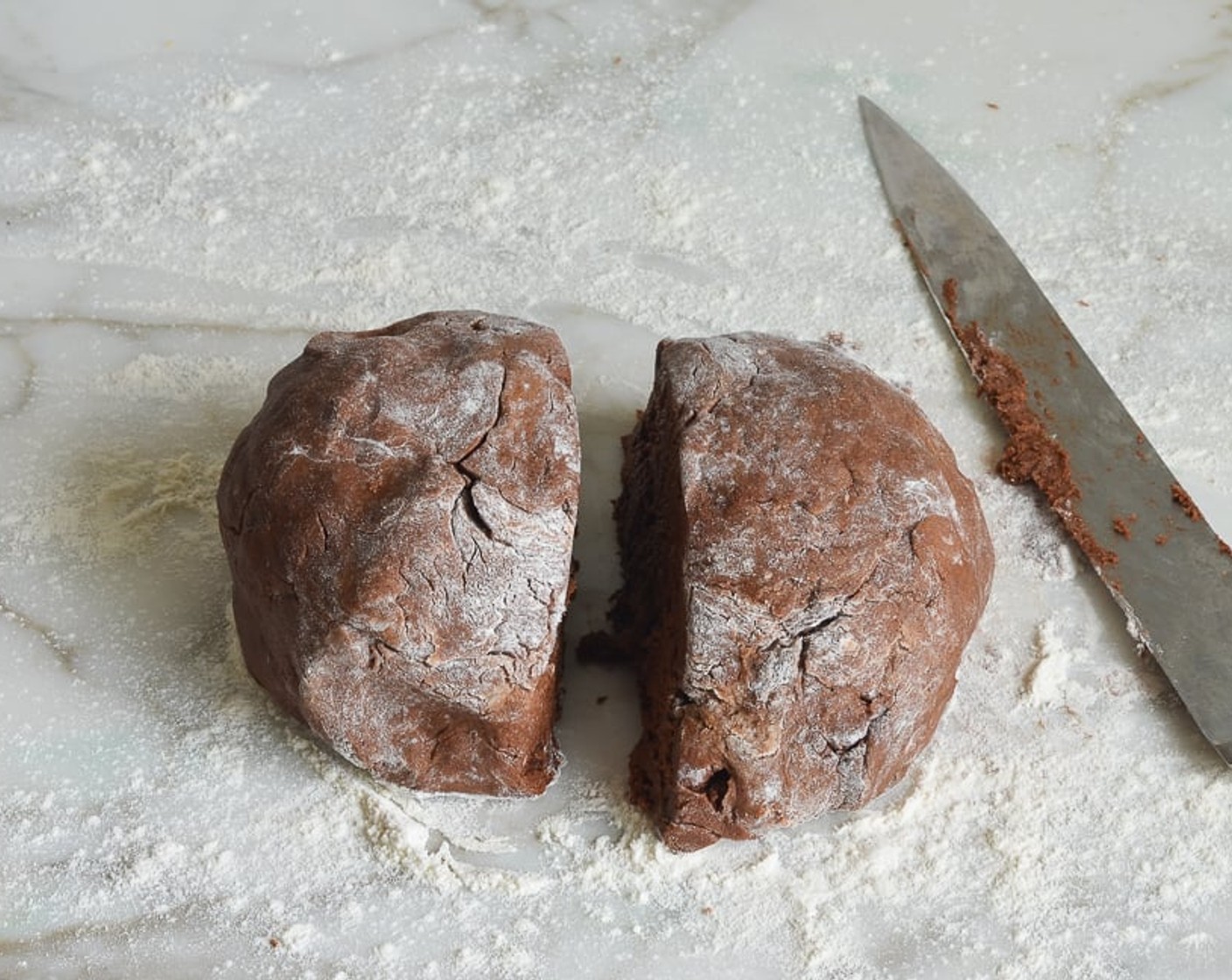 step 6 Dust a work surface with flour. Using a rubber spatula, scrape the sticky dough out onto the work surface and dust the top of the dough lightly with flour. Using your hands, shape the dough into a rough ball (if it's still too sticky, dust with a bit more flour) and cut in half.