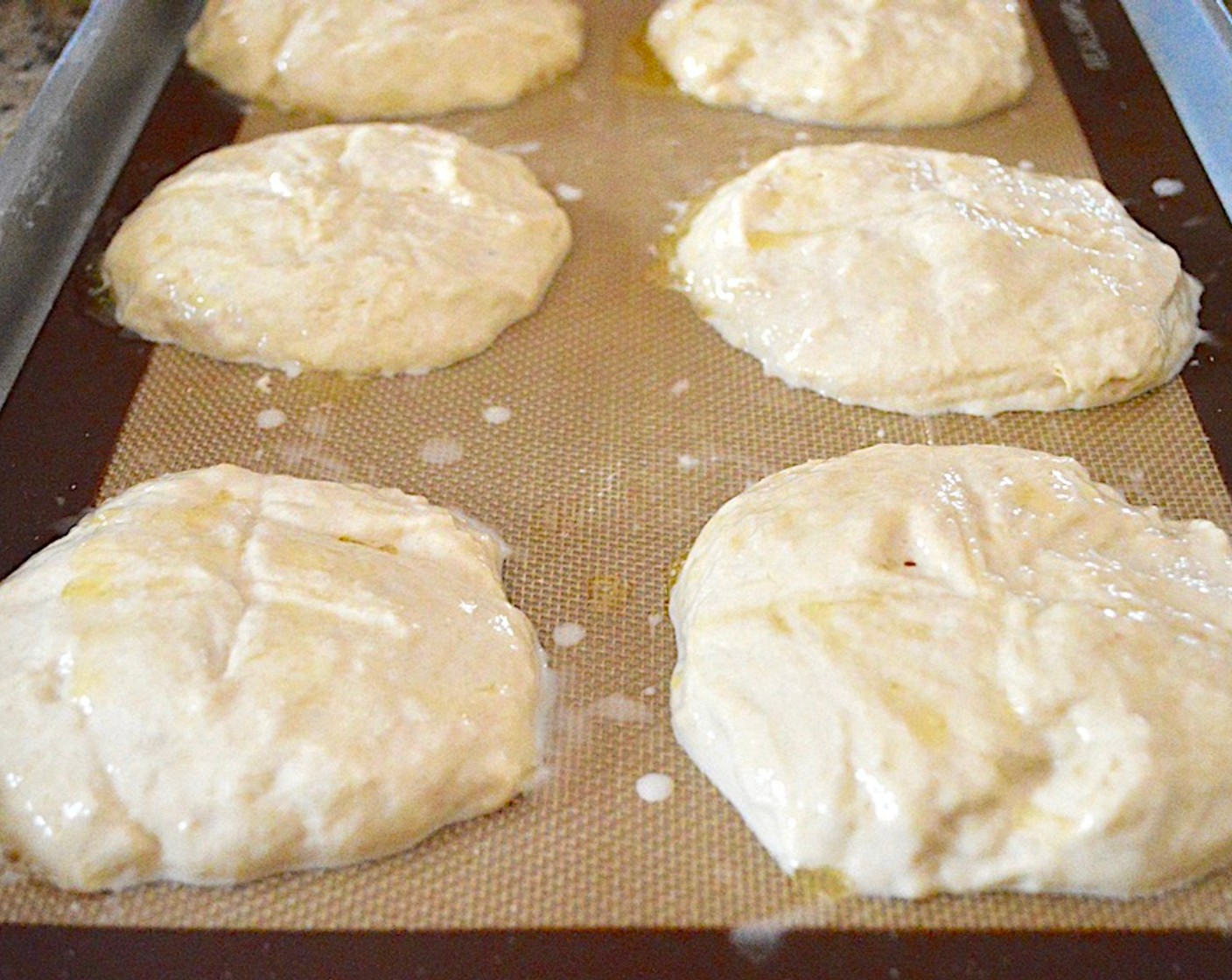 step 8 Score a plus sign on the tops of each bun for some interest, then brush them all well with the Butter (1/4 cup). Finally, sprinkle them all generously with Sea Salt (to taste) on top.