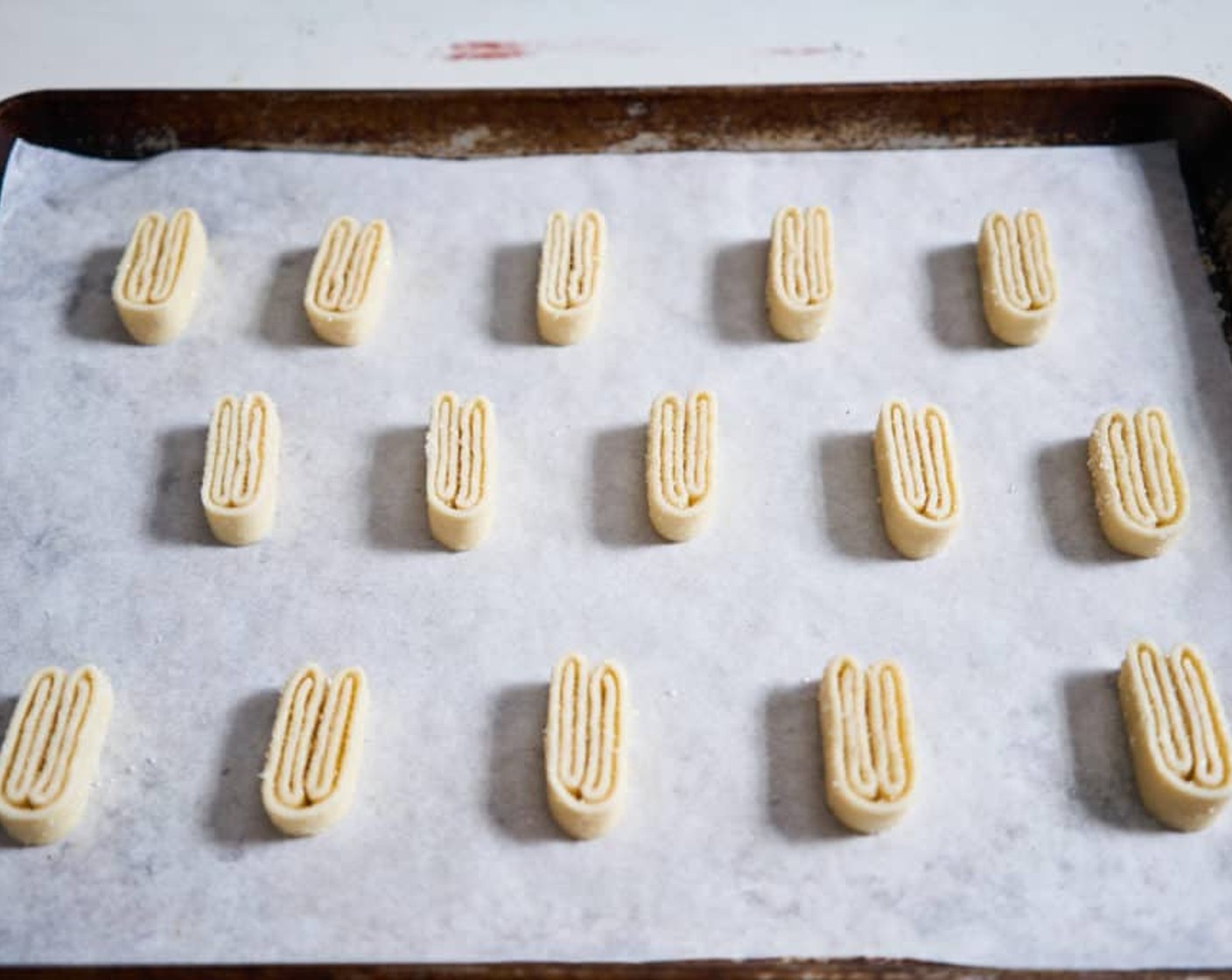 step 7 Remove the dough from the fridge and slice into ¼-inch pieces. Place the slices on a parchment-lined baking sheet cut-side down, so you can see all the little folds in the dough. Make sure the folds stay tightly together. Allow plenty of space between each one, as the dough will expand on both sides as they bake.