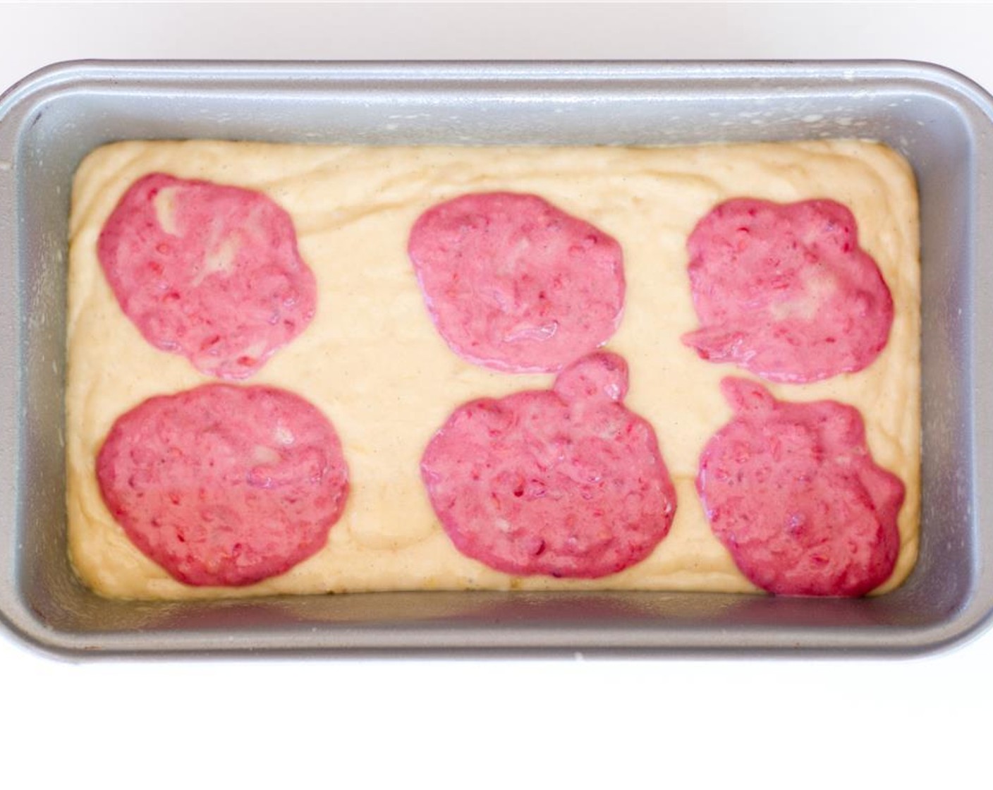 step 9 Pour banana batter in to the greased loaf pan, then add dollops of raspberry batter to the pan. Swirl the batter with a knife, being careful not to scrape the bottom of the pan, until a marbled effect is achieved.