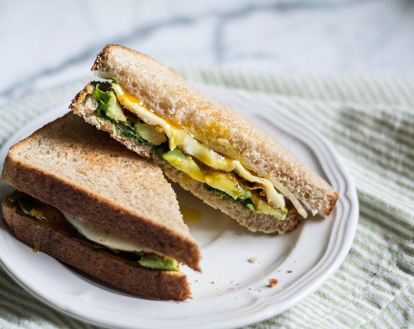 step 6 Assemble sandwiches by adding cooked eggs to the four slices of bread with spinach and avocado, then top with the other four pieces of bread with melted aged cheddar cheese.