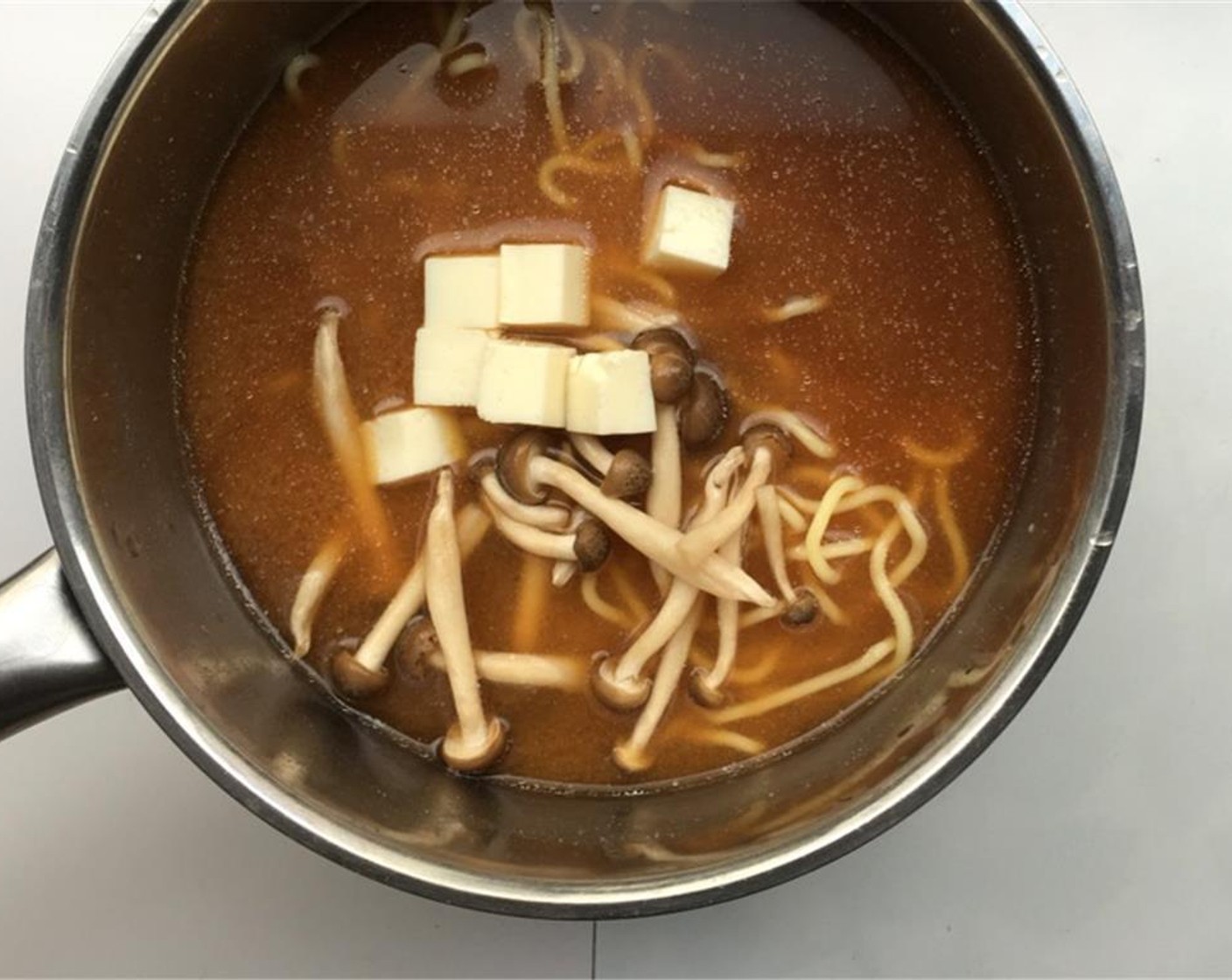 step 6 Let them soak in the miso soup for a couple of minutes until they fall apart. Then add the Tofu (2 oz) and the Mushroom (1 handful) (depending on which mushrooms you are using, slice them up if necessary). Season with some Ground Black Pepper (to taste).