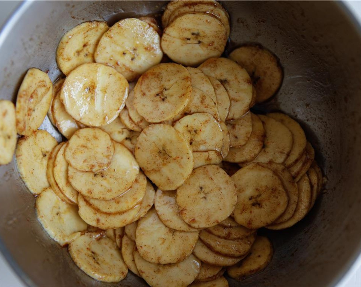 step 6 Place the sliced plantain in a bowl with the Coconut Oil (2 Tbsp), Maple Syrup (1 Tbsp), Salt (1/2 tsp), Simply Organic Cinnamon, Ground (1/2 tsp), and Cayenne Pepper (1/4 tsp). Use your hands to separate the slices and ensure they are evenly coated.