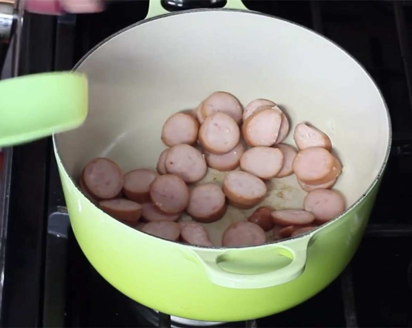 step 5 In a pot, brown your sliced sausage. Once browned, transfer to a plate and set aside.