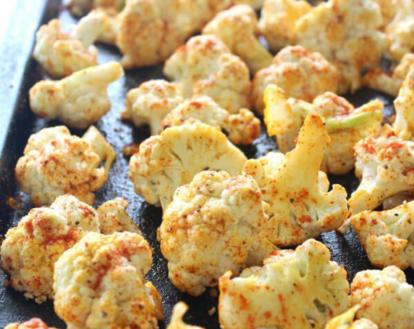 step 2 Place the Cauliflower (1 head) on a large baking tray. Drizzle with Olive Oil (3 Tbsp) and Sesame Oil (2 Tbsp). Sprinkle on the Ground Turmeric (1/2 Tbsp), Paprika (1/2 Tbsp), Ground Cumin (1/2 Tbsp), Salt (to taste), and Ground Black Pepper (to taste).
